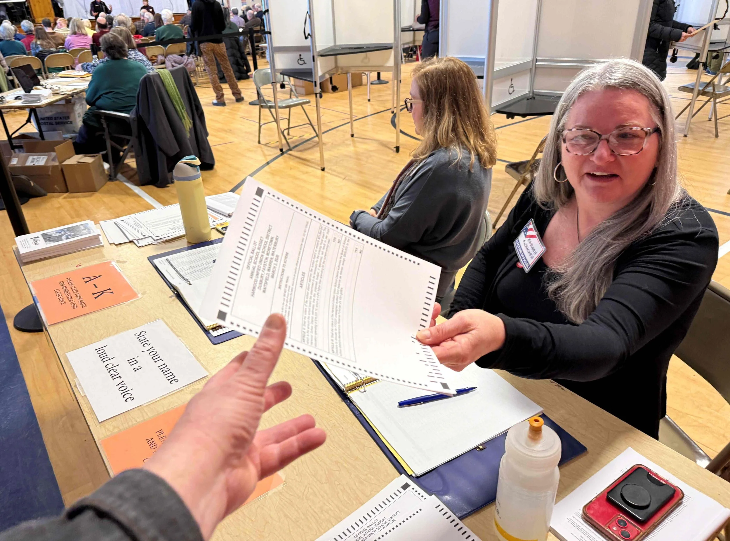   Election volunteer Maureen McCracken hands out ballots to voters. Photo by Gordon Miller   