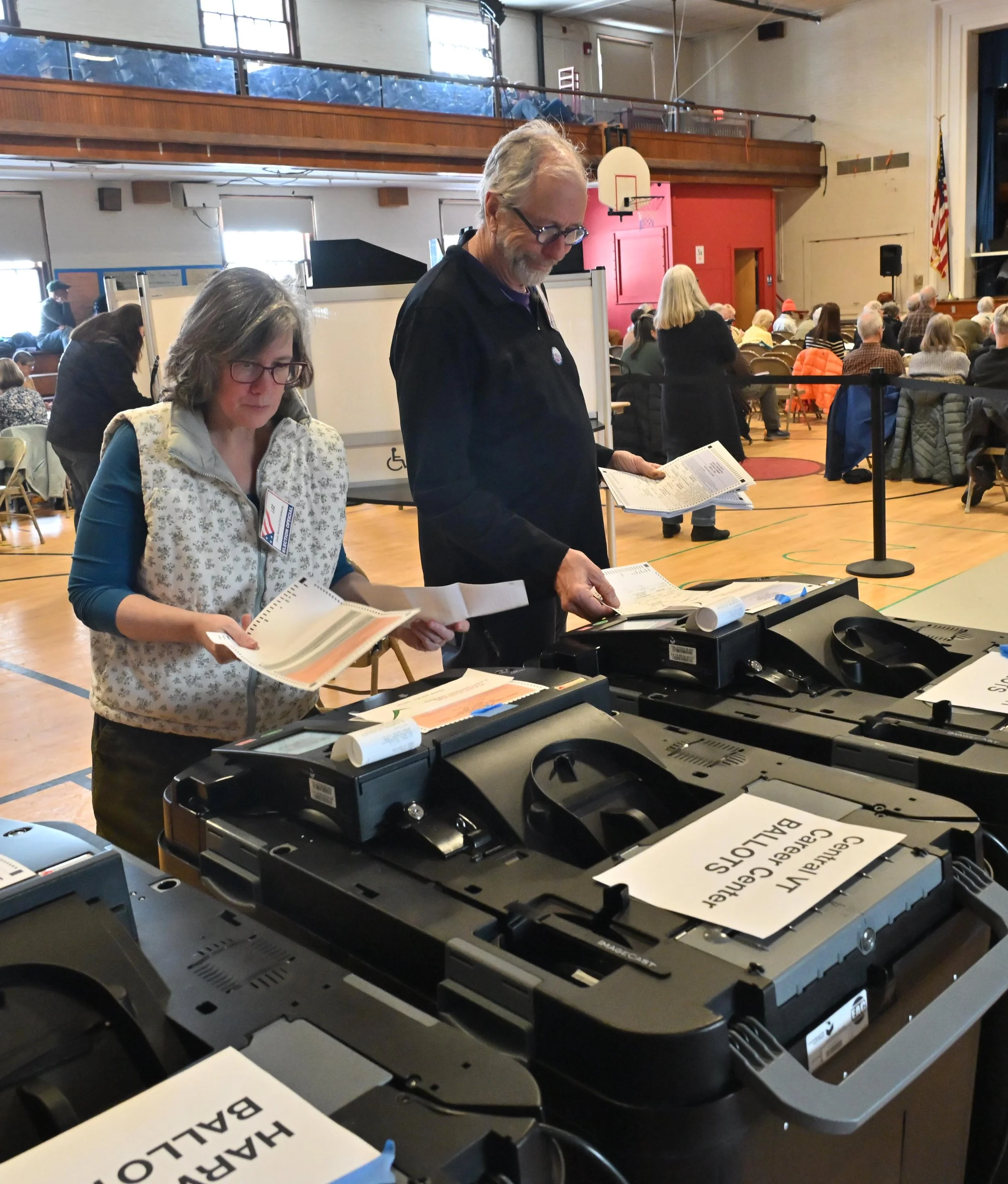   Board of Civil Authority Chair Liz Schlegel and Justice of the Peace John Bauer feed absentee ballots into tabulator machines. Photo by Gordon Miller   