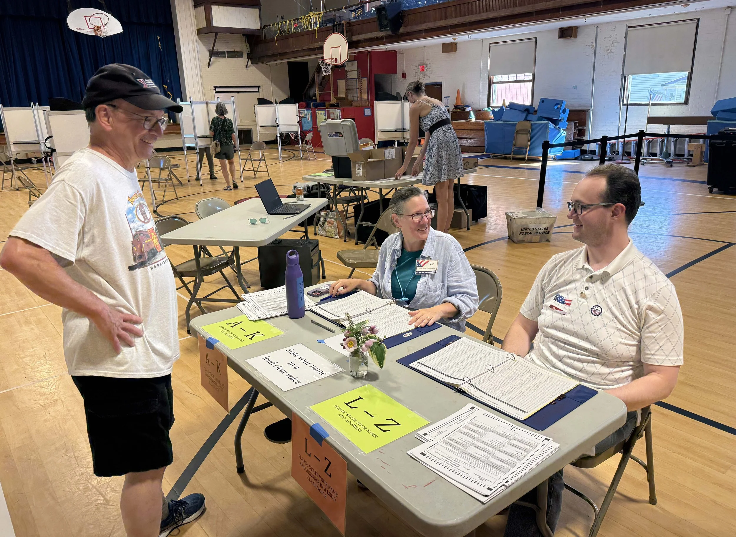   Board of Civil Authority Chair Liz Schlegel offers to switch spots at the voter check-in table with Evan Hoffman. Photo by Gordon Miller  