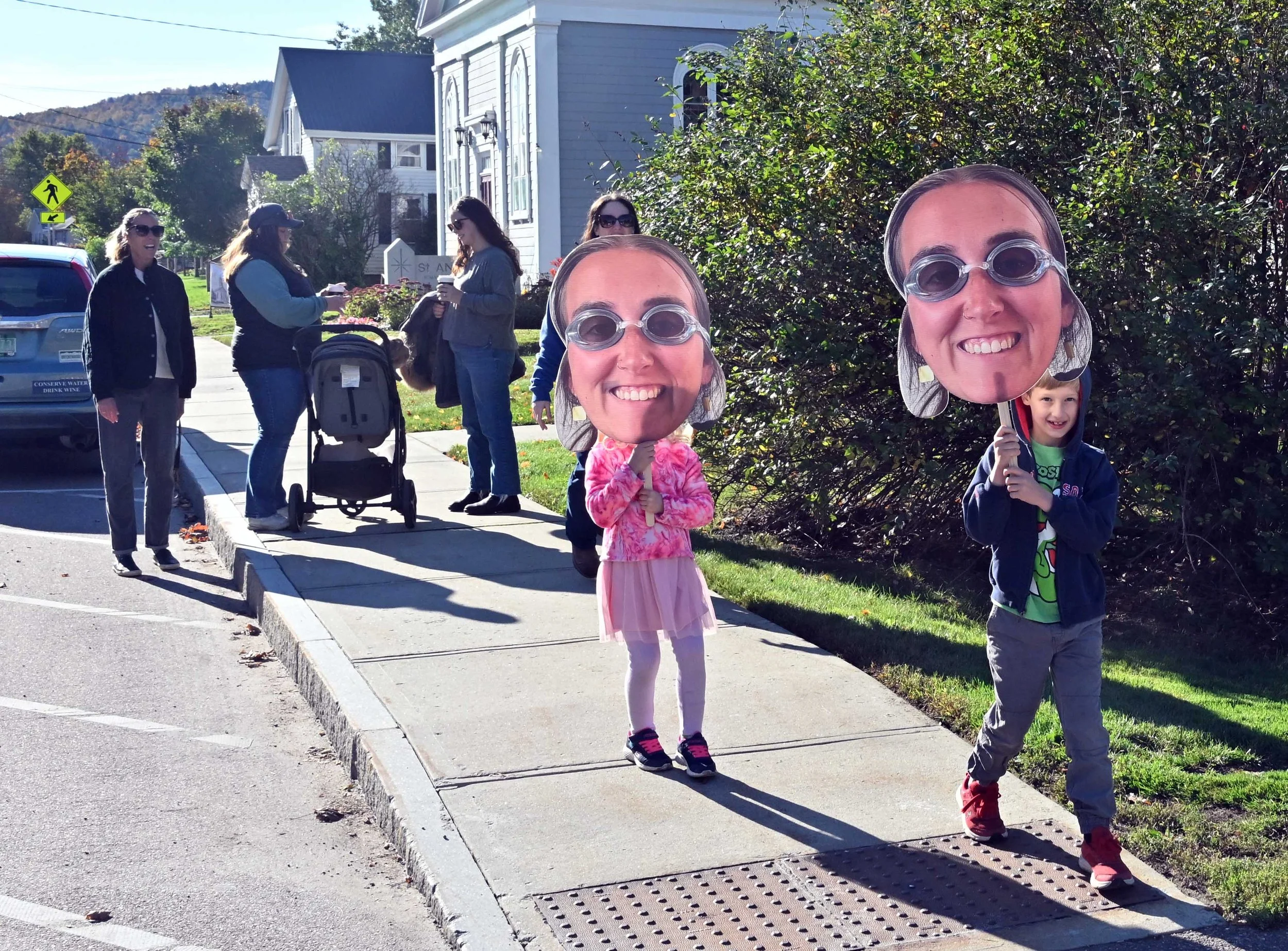   Margot and Miller Daubenspeck carry larger-than-life images to cheer on 5K runner, Maggie Cosgrove, 24, from Waterbury. Co-workers at Hunger Mt. Children's Center made the posters. Cosgrove finished 87th out of 155 runners. Photo by Gordon Miller  