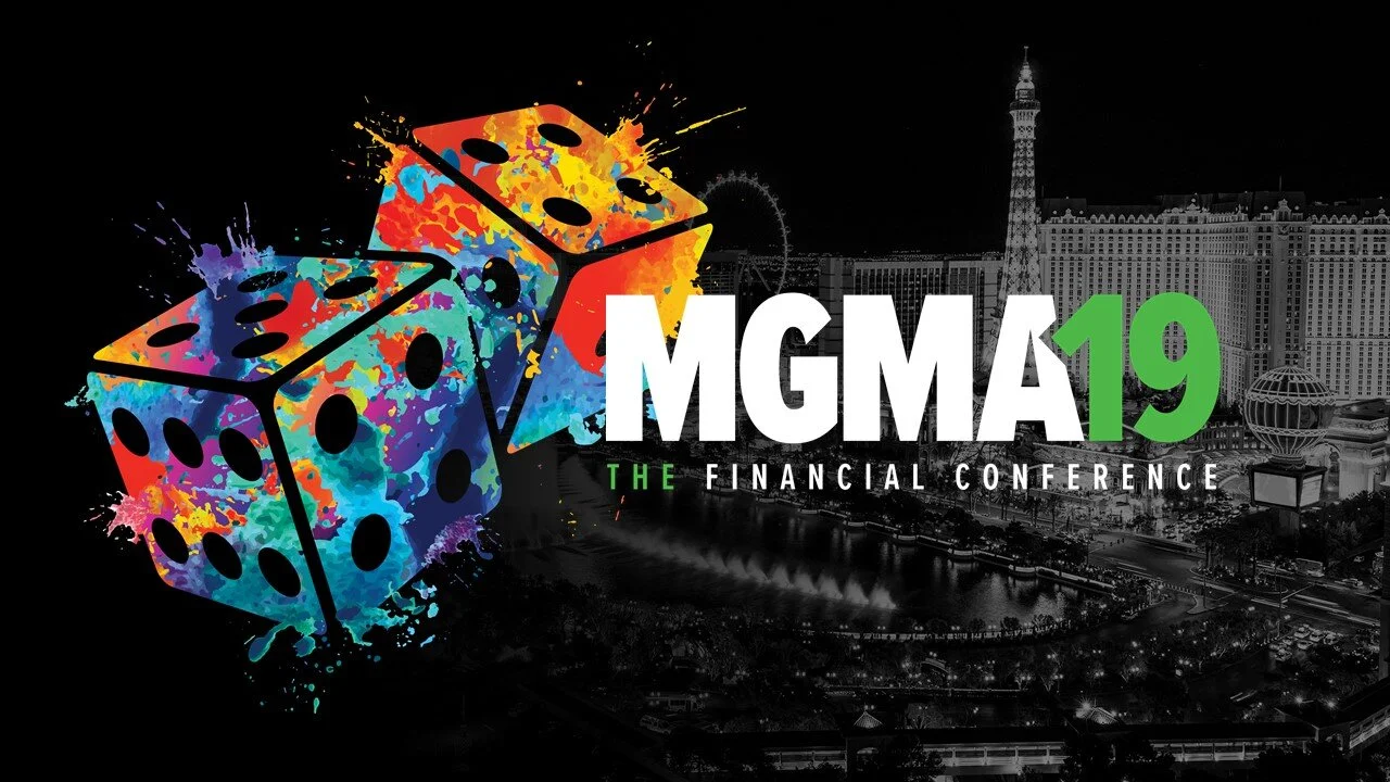 Colorful dice with "MGMA19 The Financial Conference" text over a black-and-white Las Vegas background.