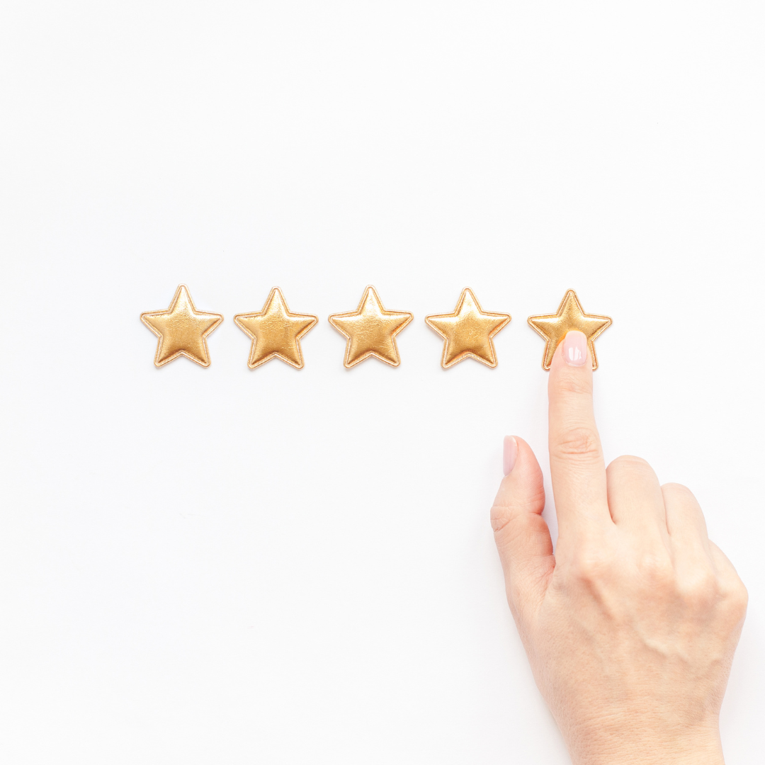 Hand pointing at fifth gold star in a row on white background