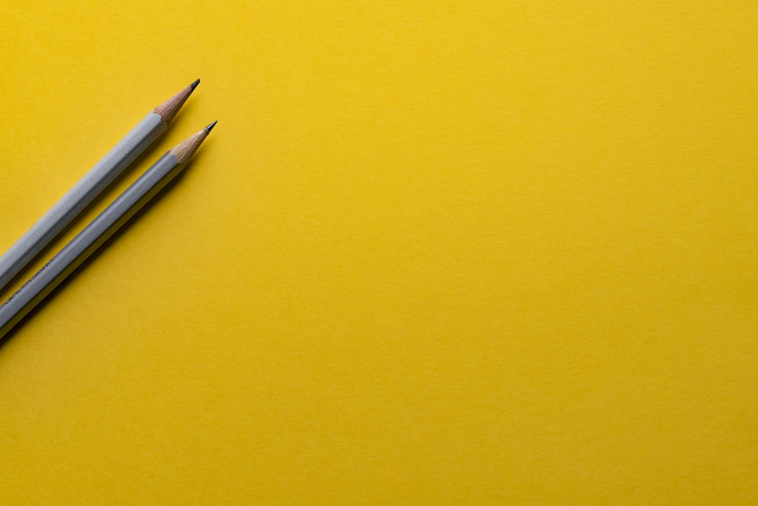 Two pencils on a yellow background.