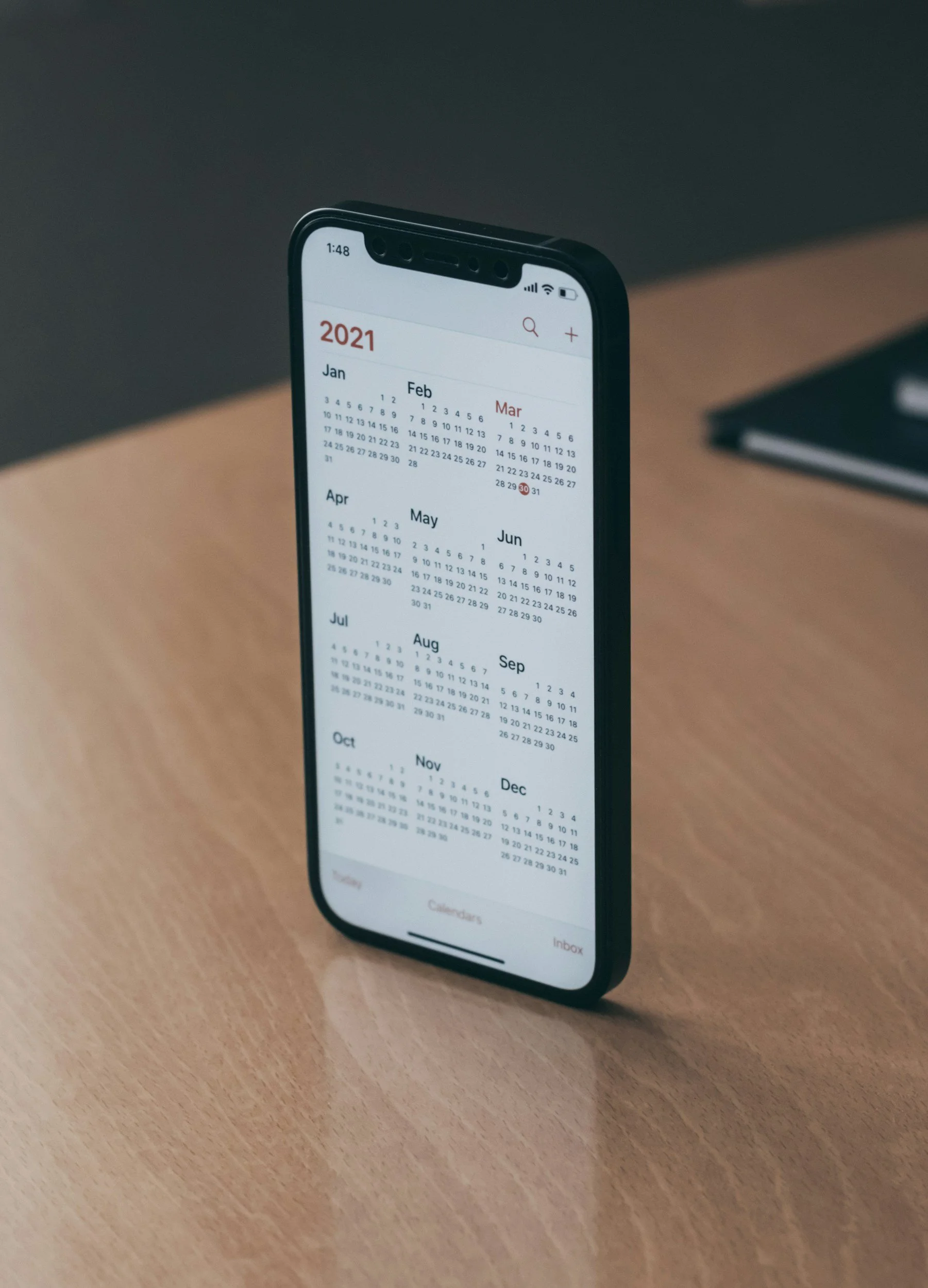 Smartphone displaying 2021 calendar on wooden table.