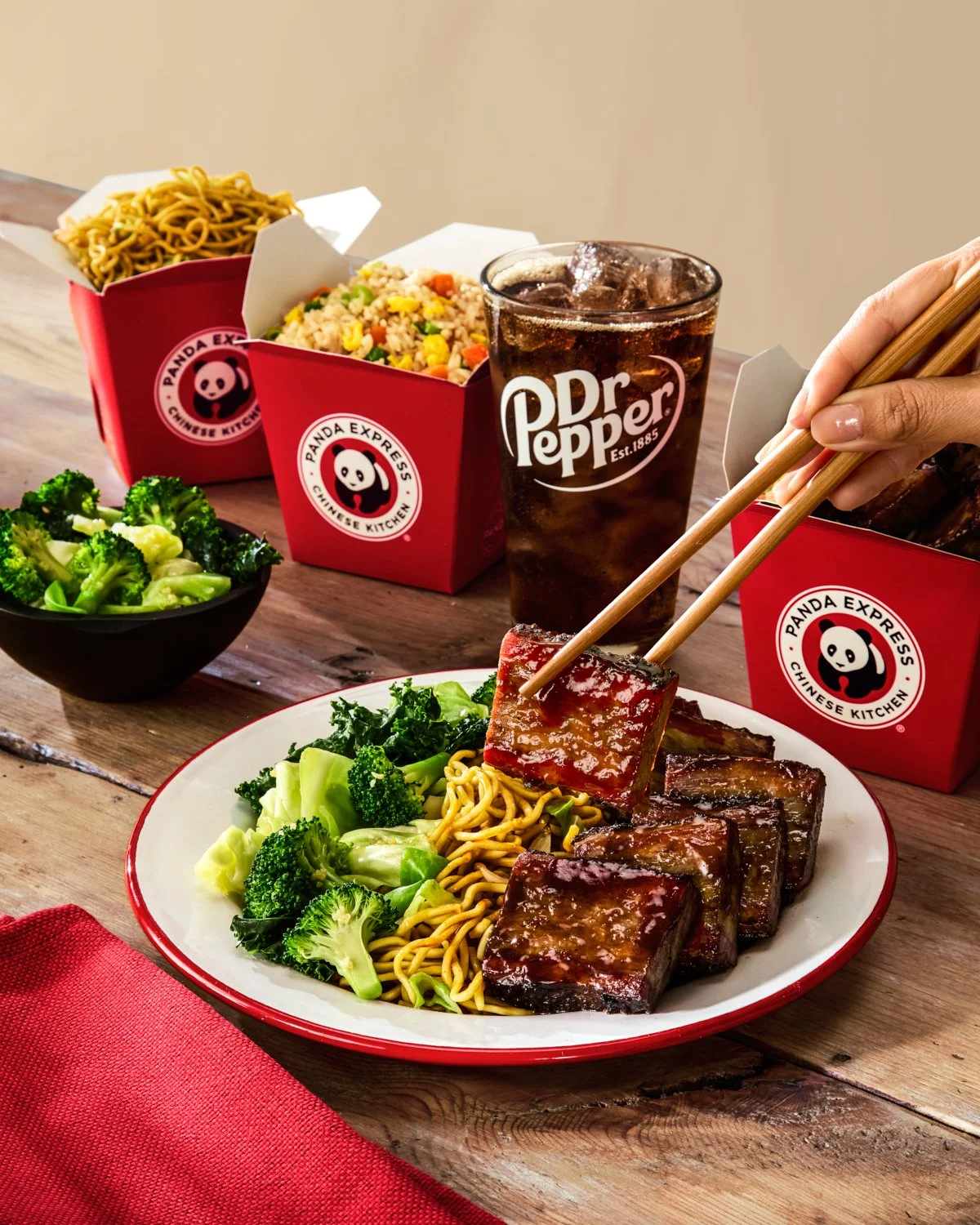 Panda Express Cantonese BBQ Brisket being plated by hand with premium brisket, chow mein, and broccoli for restaurant advertising.