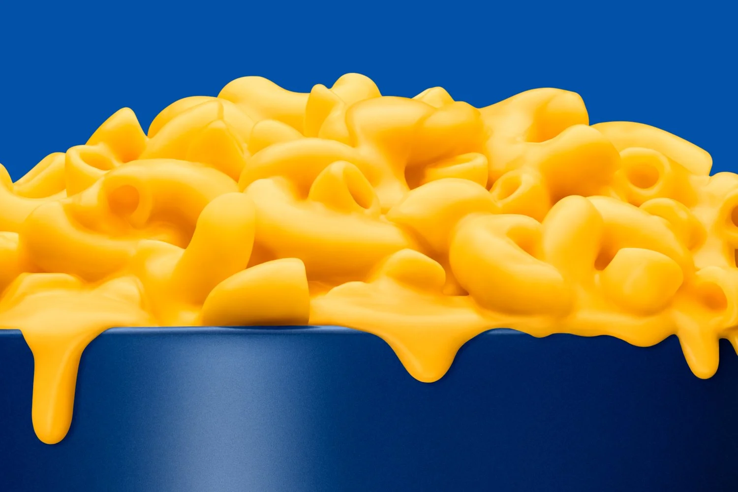 Mac and cheese overflowing from a cobalt blue bowl