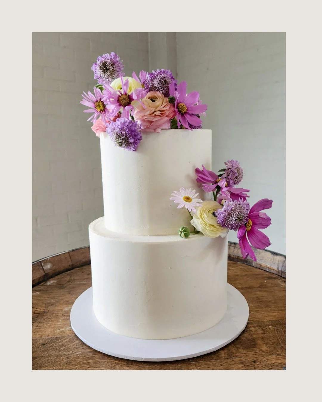 A sweet celebration featuring two tiers of white ganache perfection in delicious white chocolate strawberry and caramel with chocolate.

Finished in smooth white ganache and dressed with blooms from @thebloomfolk  this beauty was the perfect match fo