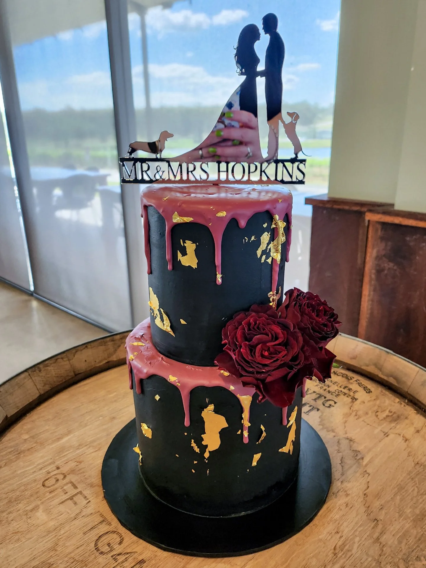 Mr &amp; Mrs Hopkins 🌹

Creating this two-tier black ganache cake in delicious Chocolate with white choc + Orange &amp; poppyseed, finished with burgundy drip and gold accents to complete the look. Topped with their custom topper 🐾

Bold, moody and