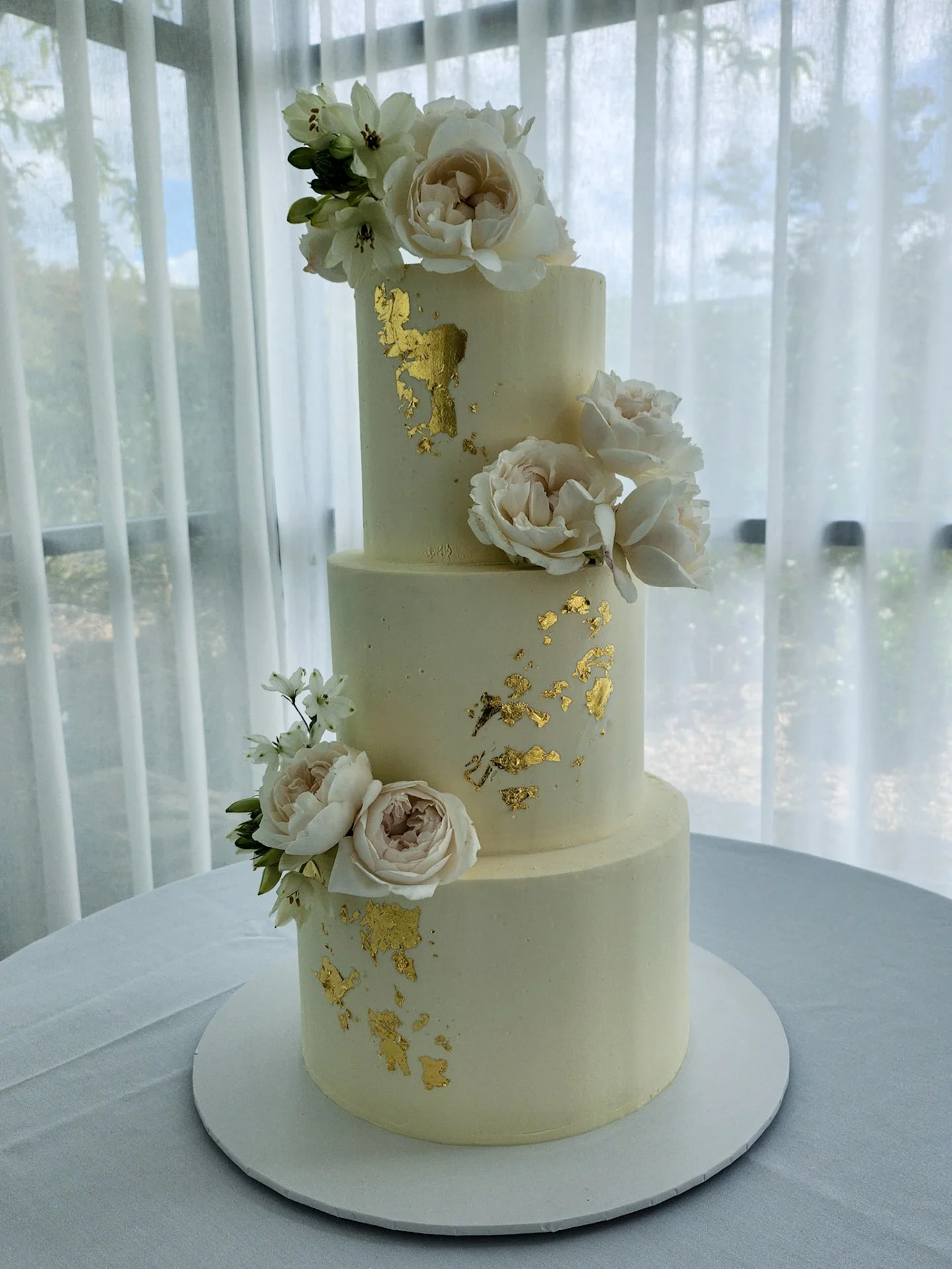 A timeless three-tier delight in white chocolate &amp; raspberry + passionfruit for Hannah &amp; James on their special day @greystoneestate_huntervalley 🤍

Finished in smooth white ganache with delicate gold leaf accents scattered across each tier,