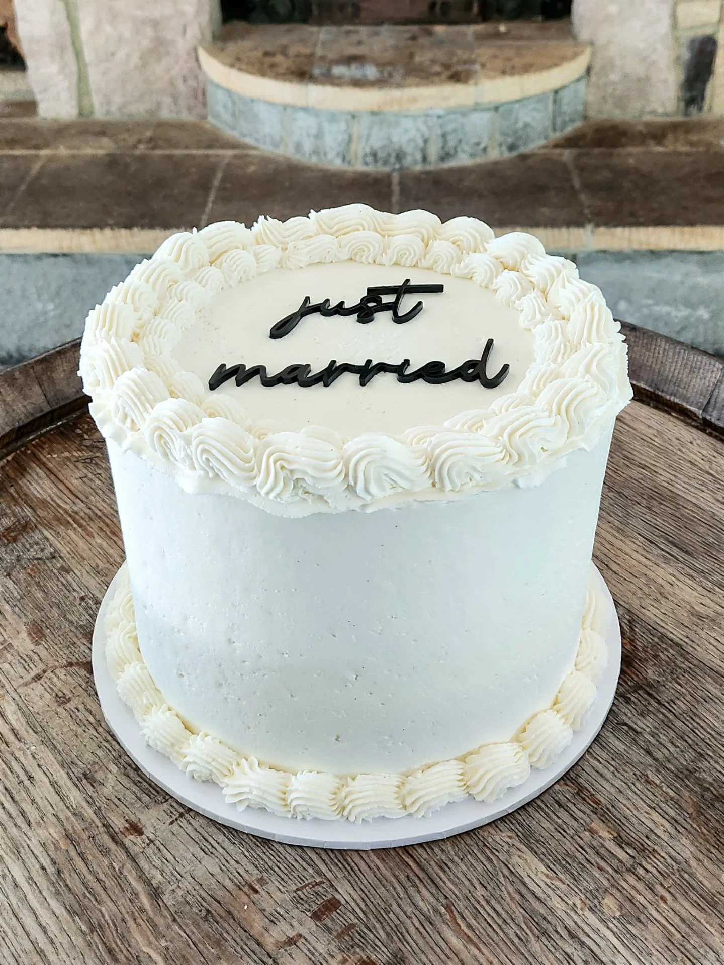 A timeless single-tier beauty for Ashlee &amp; Riley's wedding, delicious chocolate inside, finished in smooth white buttercream with delicate shell piping topped with a bold &ldquo;just married&rdquo; for that perfect modern contrast against a class