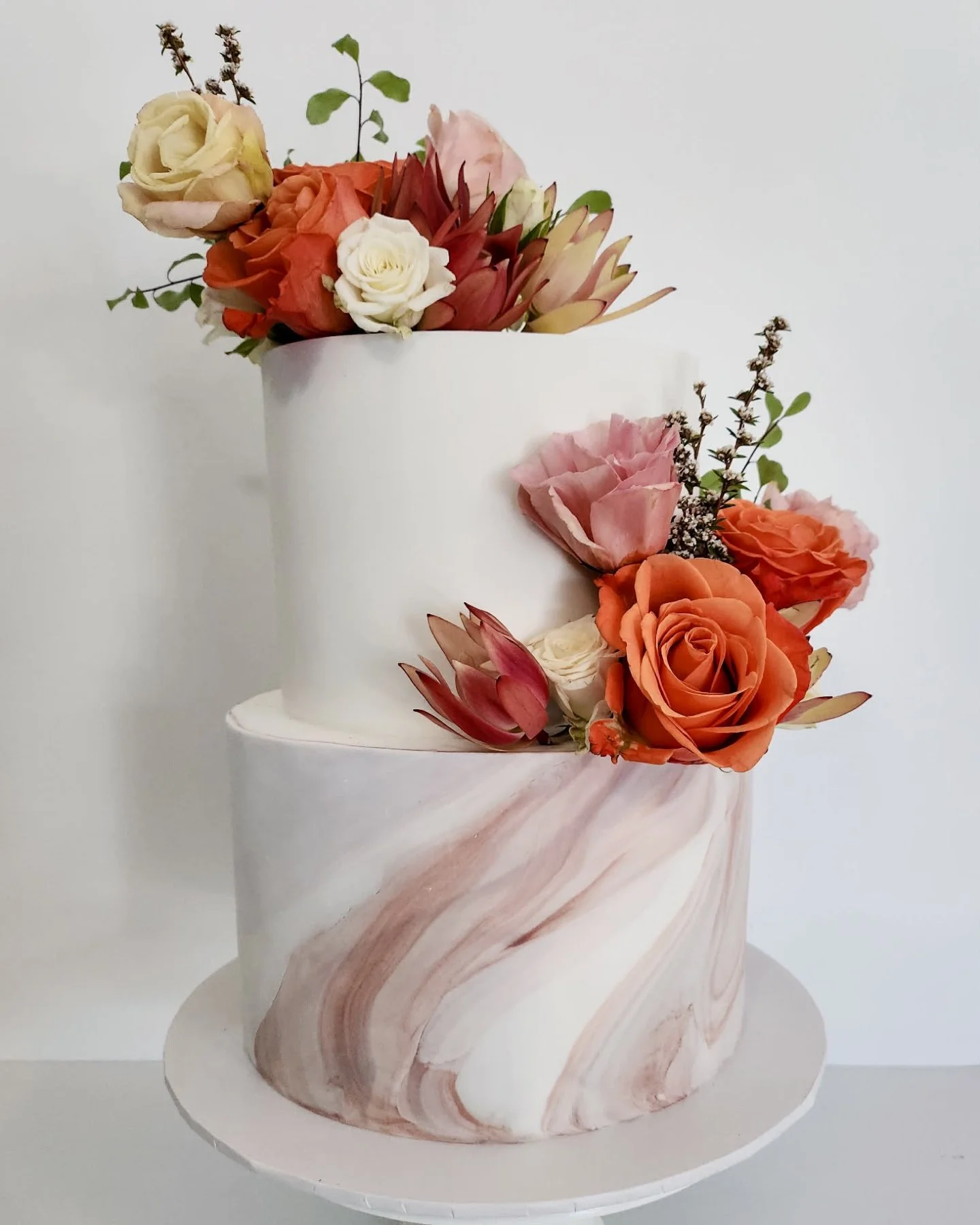 This two-tier design featured red velvet and zesty citrus, the perfect balance of rich and fresh.

Finished in smooth white fondant with a soft marble feature to colour-matched to their invitation suite for a beautifully cohesive look. Adorned with s