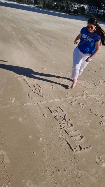 A girl jumping over her line drawn in the sand with the words “Future” and “Past” written on a beach