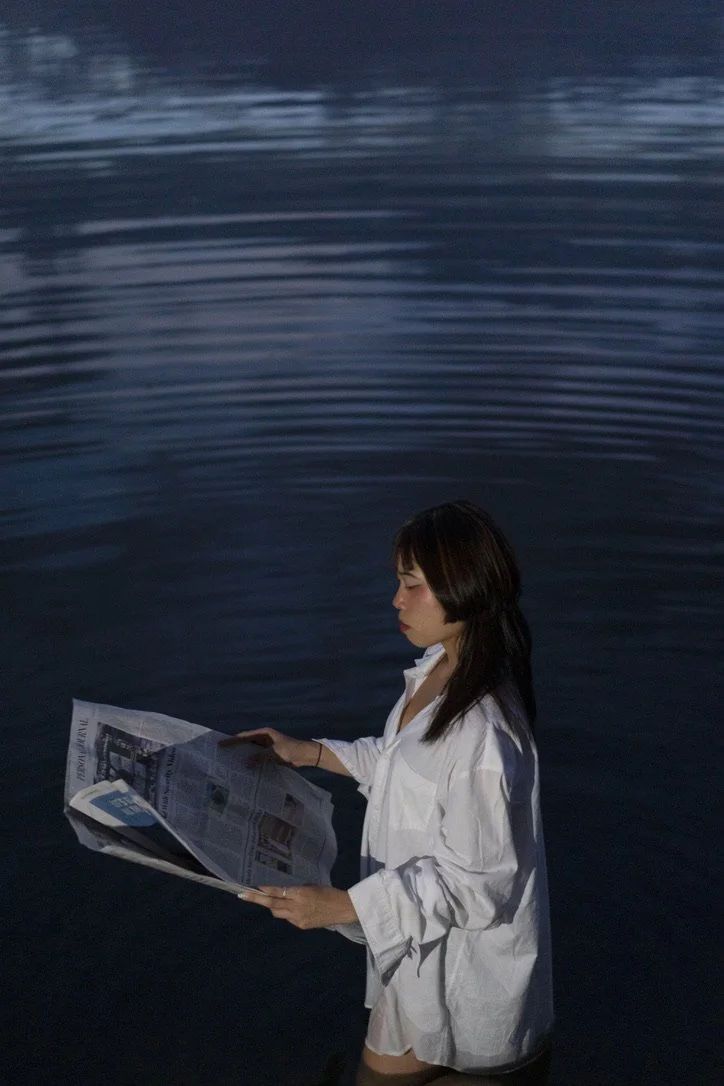 Girl holding newspaper by lake