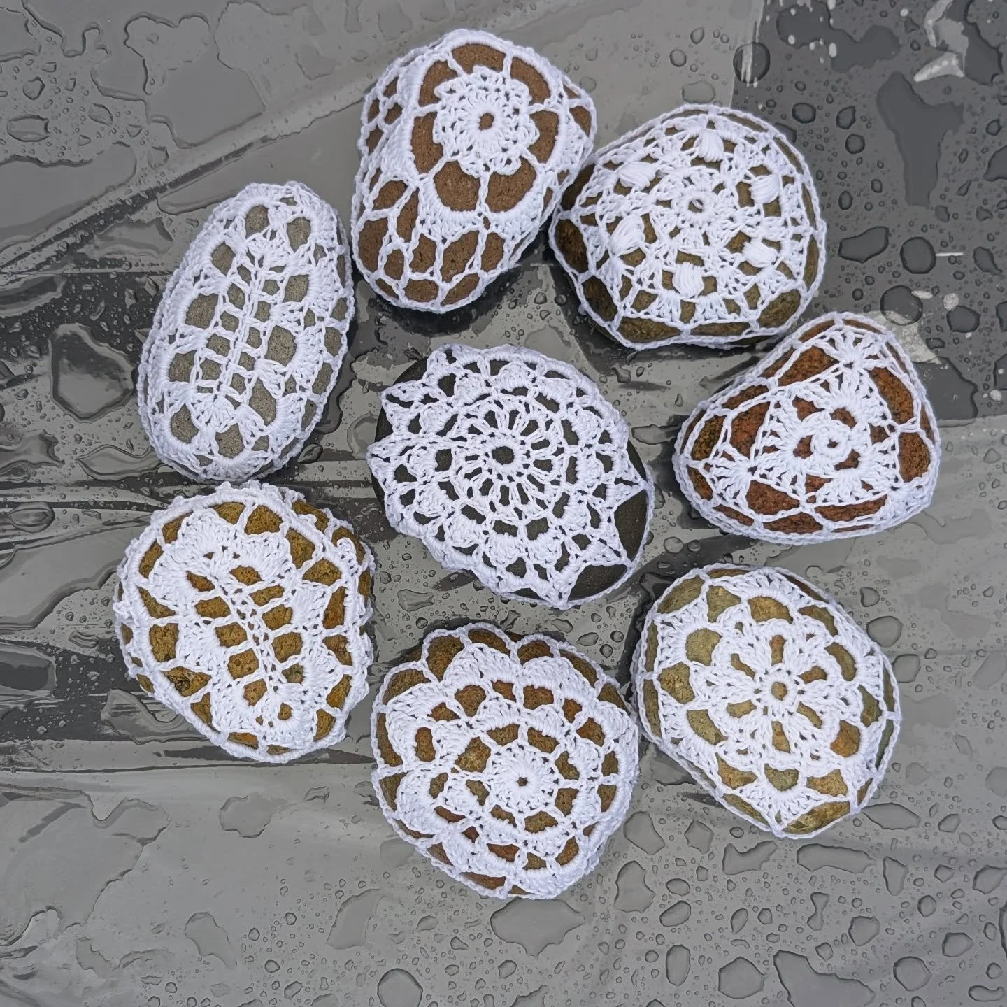 Rocks from the beach - Cotton from the field -  With a Crochet Hook and Nibble fingers I created the fancy fittings of these 8 naked rocks. Their purpose isn't just to look pretty, but to hold the table cover down when the wind blows wild. When they 