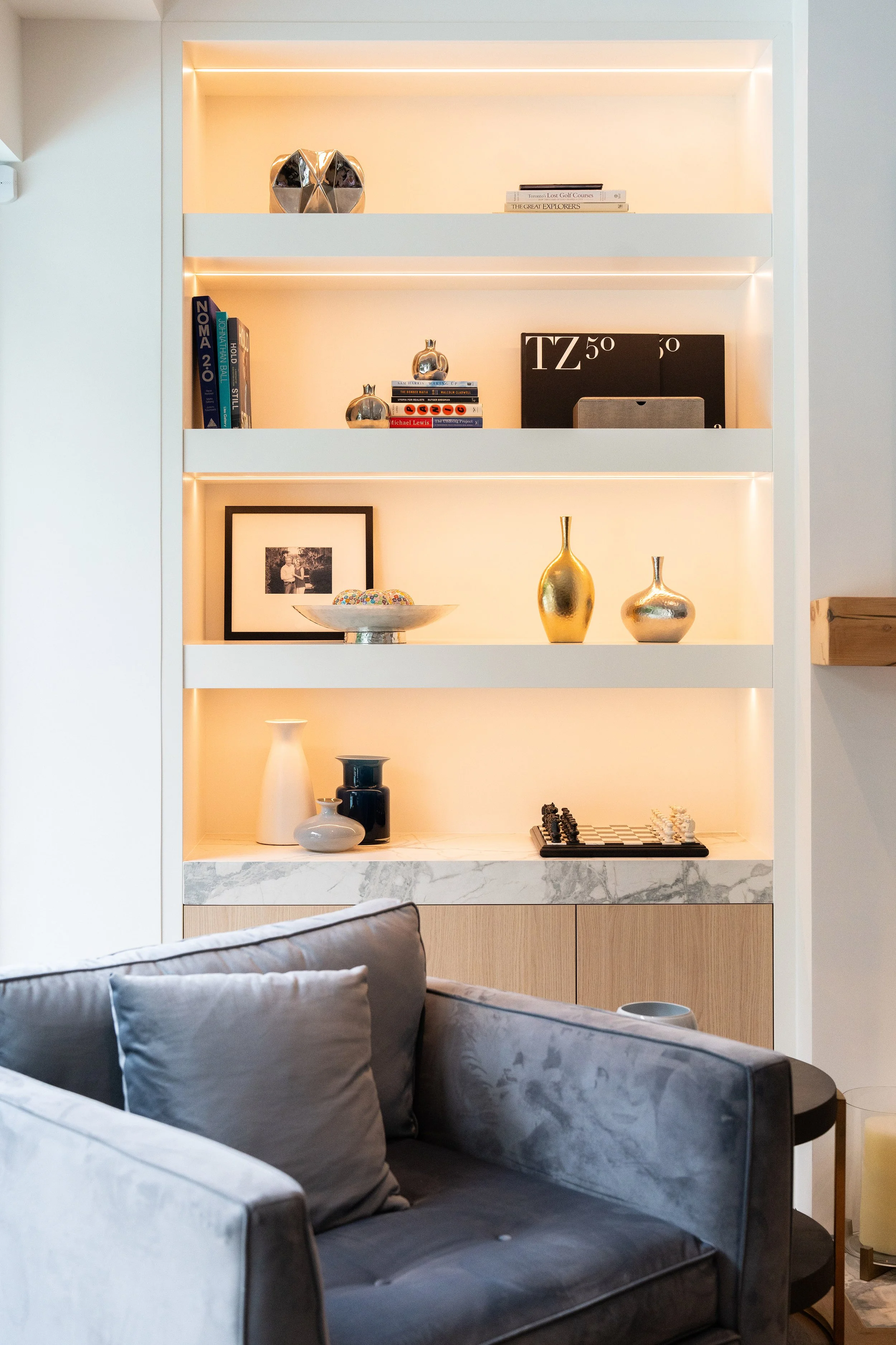 Decorative shelves with books, vases, framed photo, and decorative objects in a well-lit, modern living room.