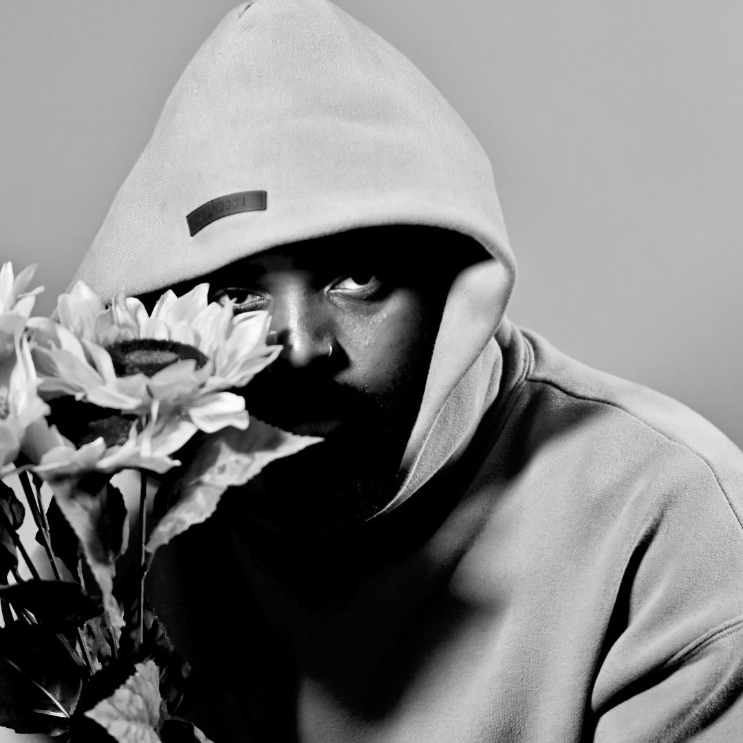 Black-and-white portrait of Yestrdy holding sunflowers, showcasing the Compton artist’s cinematic visual style.