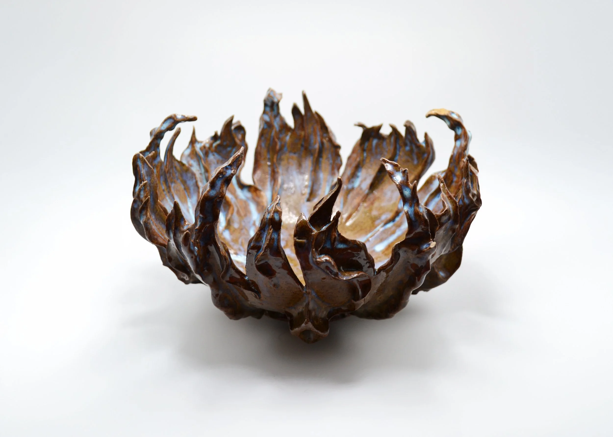 A close-up of a sculpture resembling a flower or a claw with intricate petal-like structures, set against a plain white background made by artist Allison Genereaux of Alcove Ceramics.