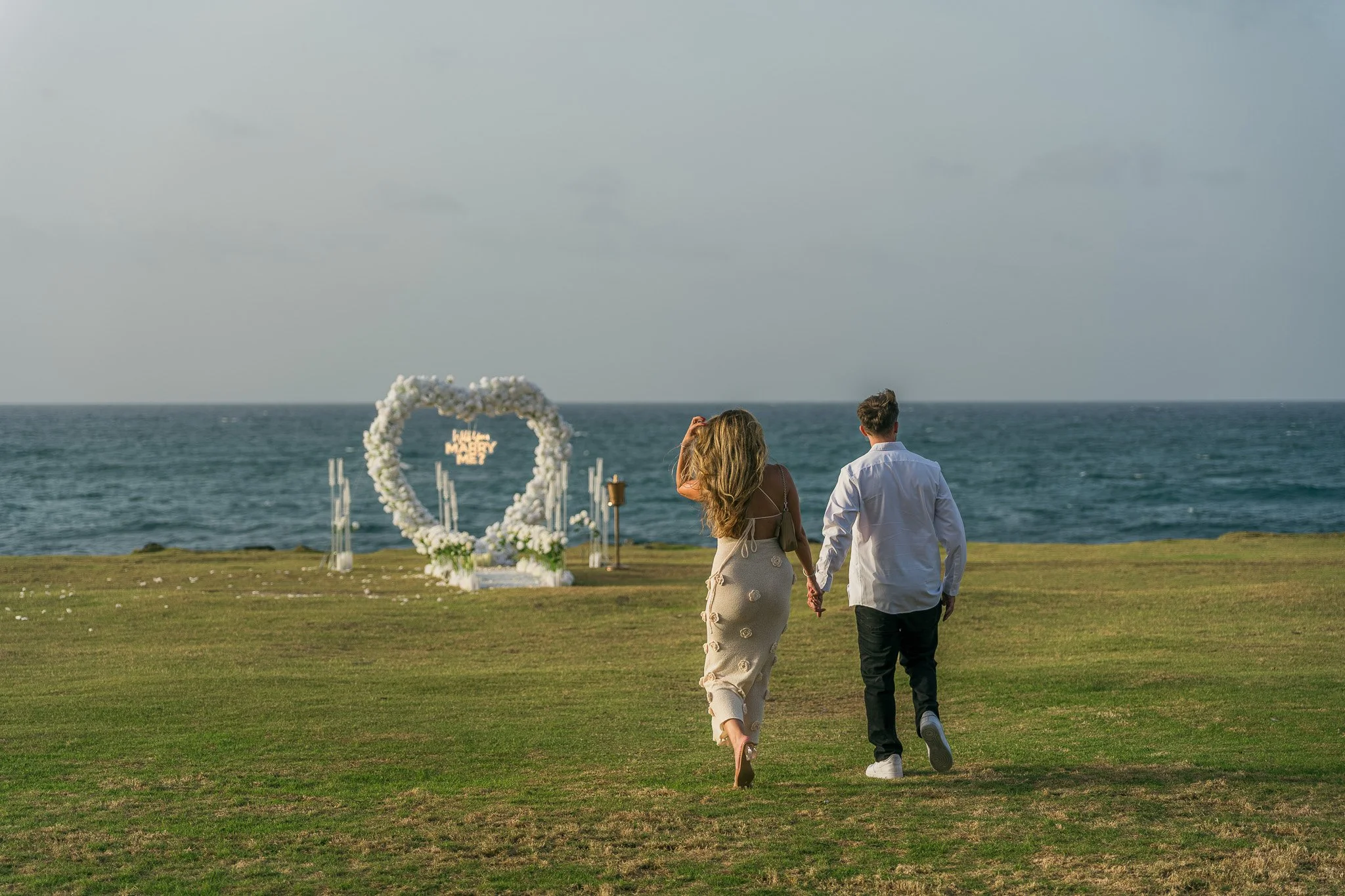 Editorial portrait of a couple walking to a luxury marriage proposal decoration in Escambrón Beach during their engagement session in Puerto Rico