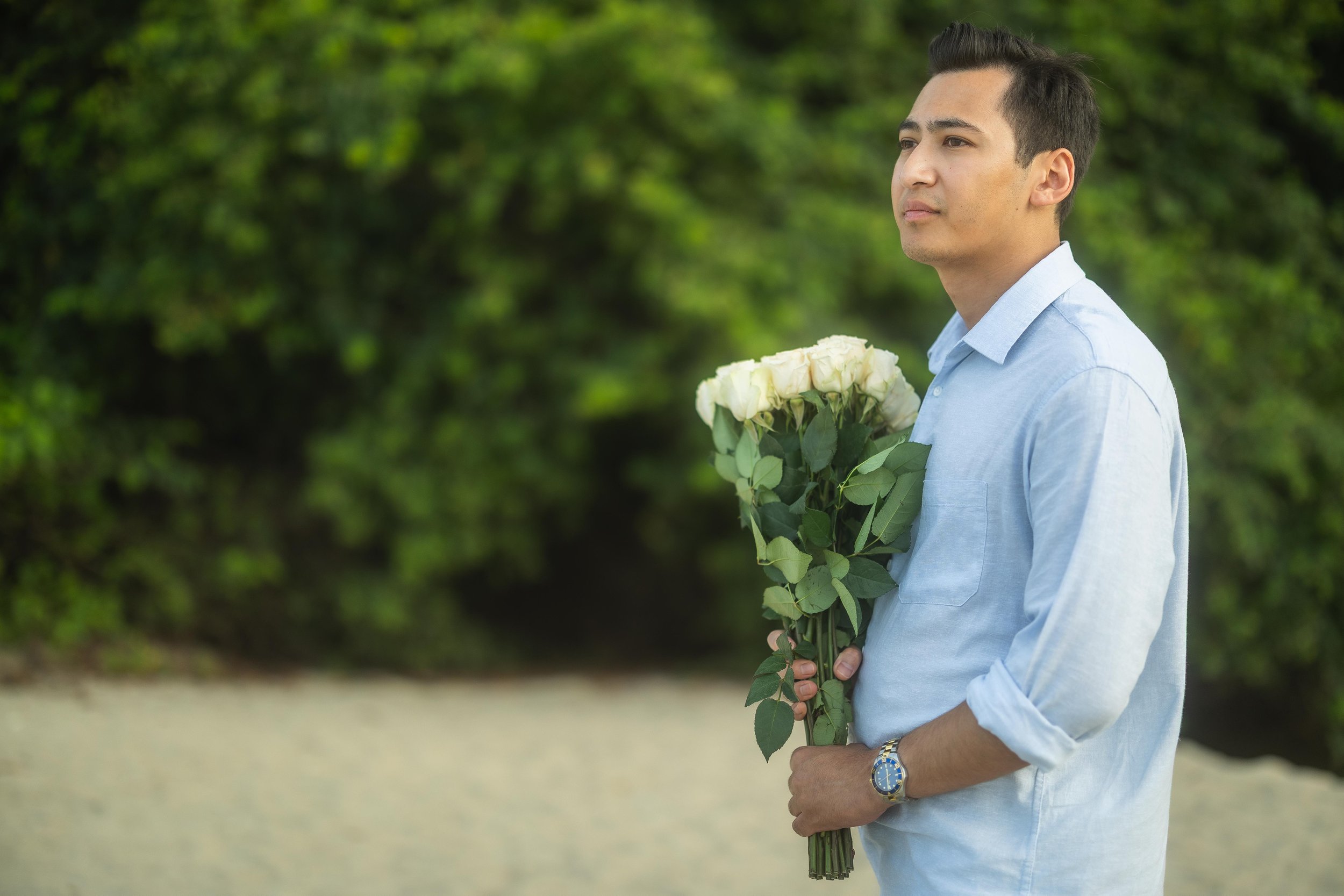 Brijend holds a bouquet of white roses while preparing for his surprise marriage proposal to Sumi on a beach in Fajardo, Puerto Rico.