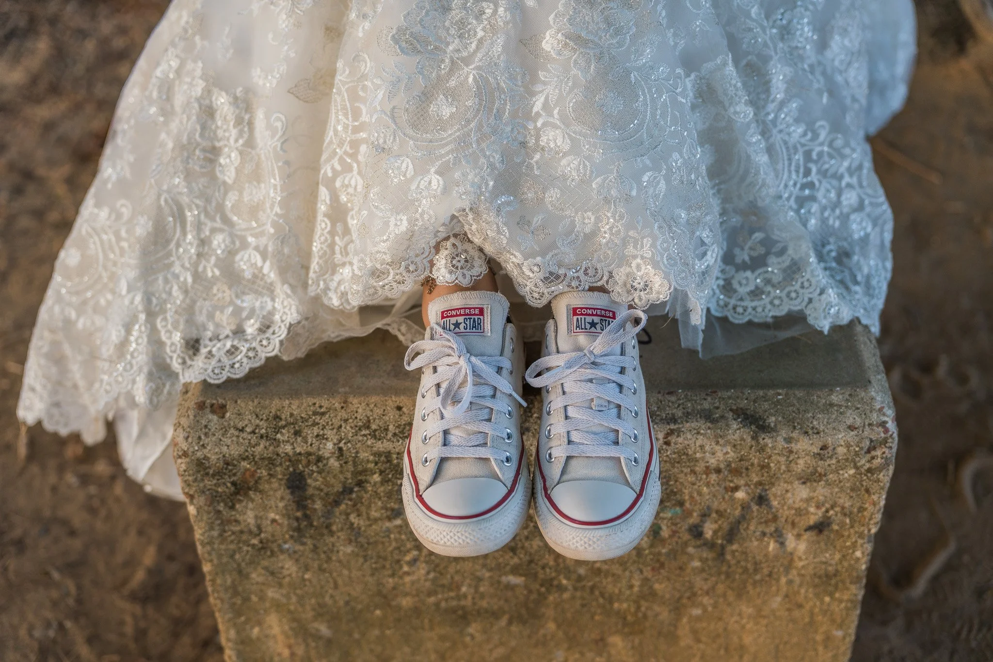 Bride wearing classic white Converse sneakers beneath her lace wedding dress during a fun and modern destination elopement in Puerto Rico.