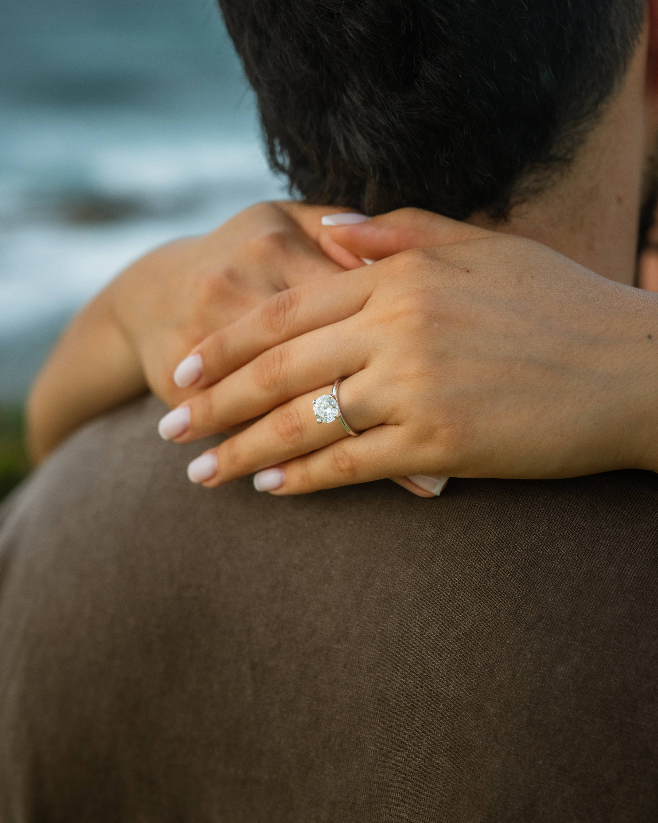 Romantic engagement portraits on beach rocks near crashing waves