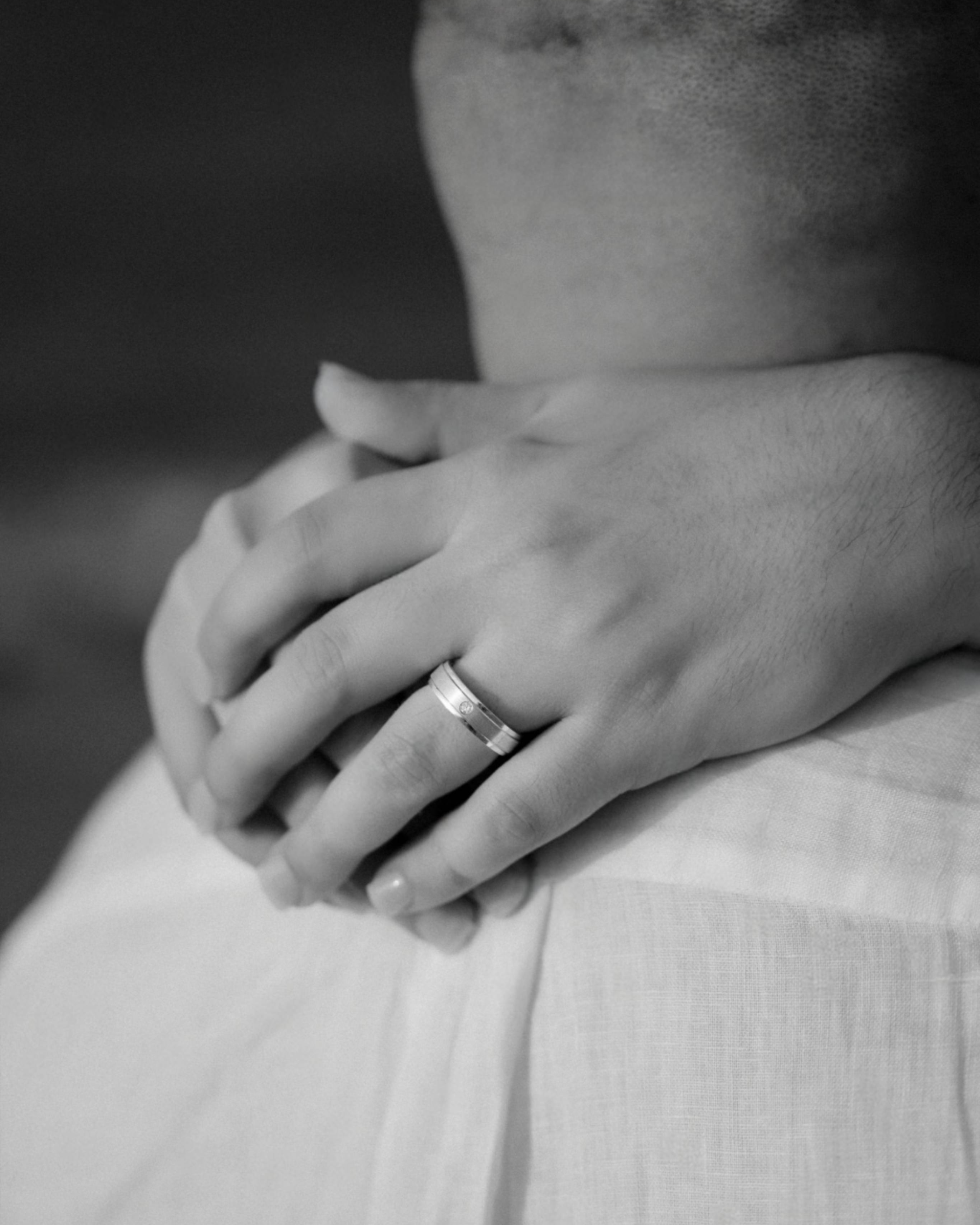 Close-up black-and-white photograph of an engagement ring resting on a groom's hand during an intimate LGBT marriage proposal photographed in Puerto Rico.