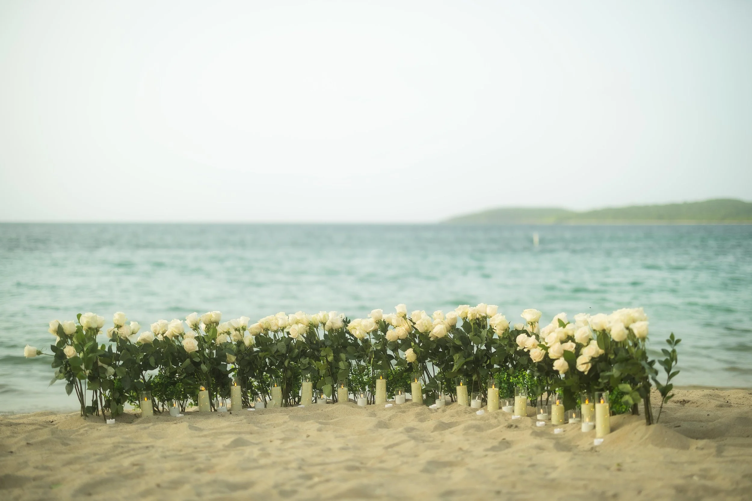 White rose and candle arrangement overlooking the Caribbean Sea at Seven Seas Beach, created for a surprise marriage proposal in Puerto Rico