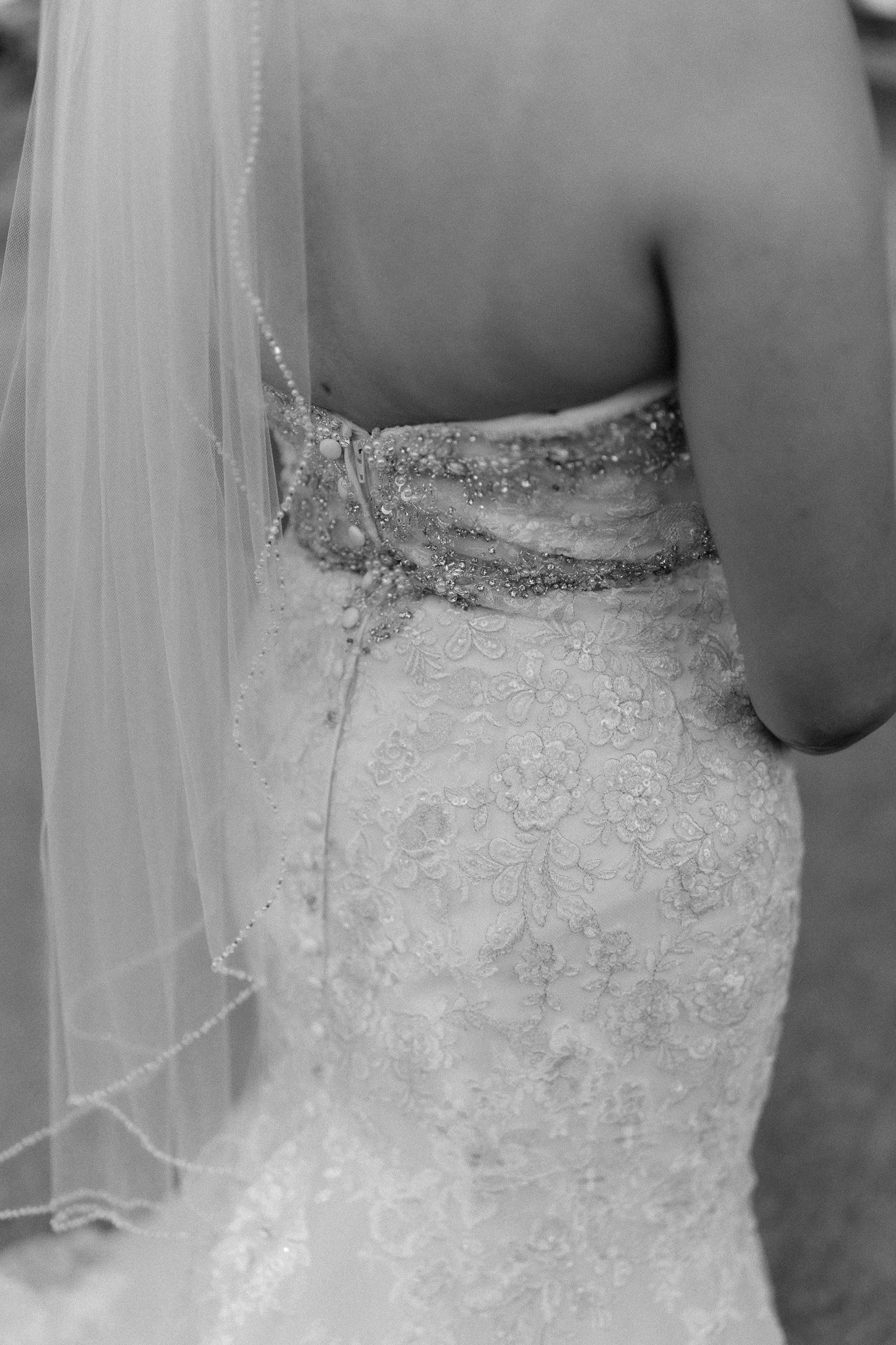 Black and white close-up of the intricate lace details and pearl-trimmed veil on a luxury wedding dress during a Puerto Rico destination elopement.