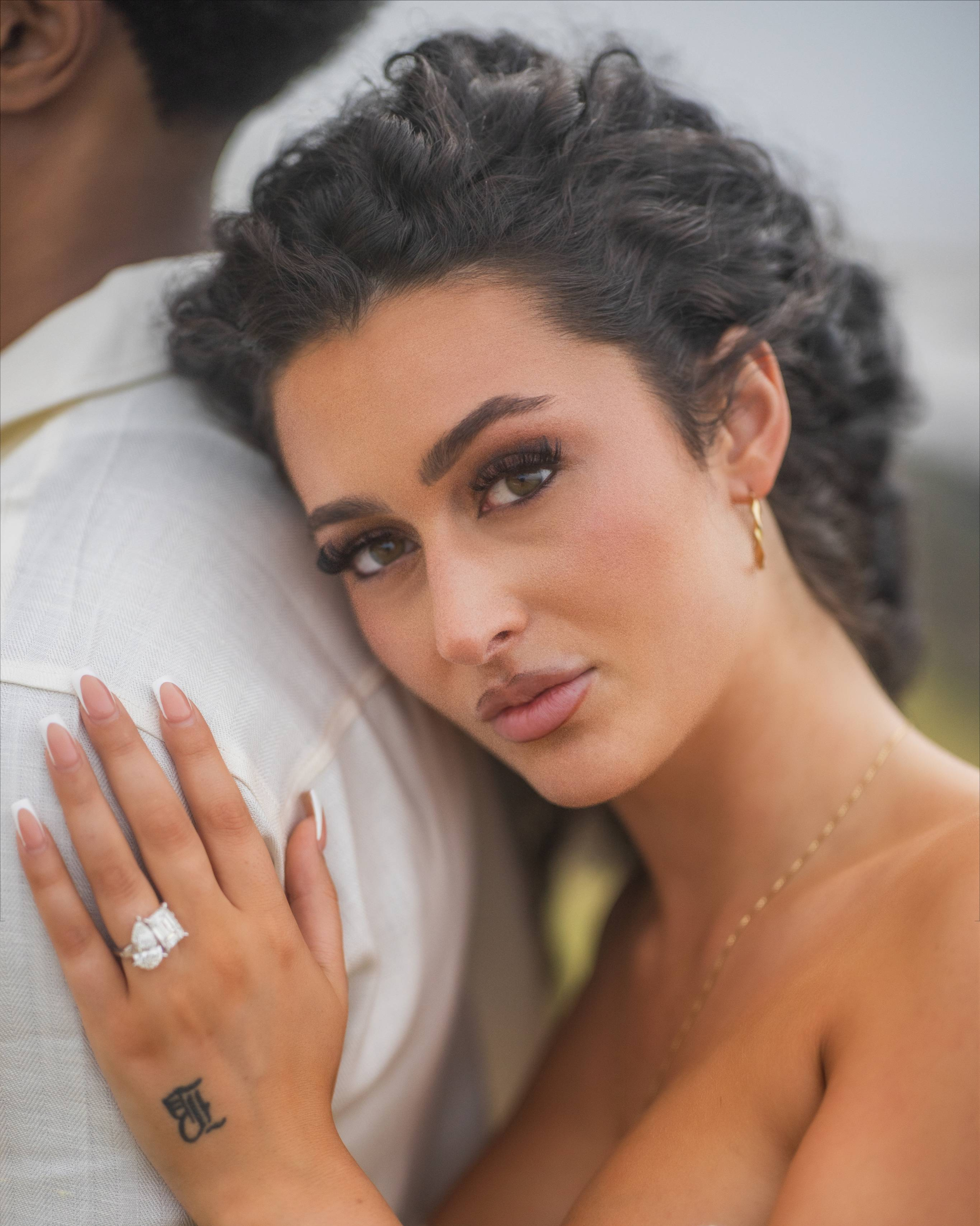 Close-up portrait of newly engaged Kathleen resting on Zeb Jackson's shoulder while displaying her custom diamond engagement ring during a luxury Puerto Rico proposal.