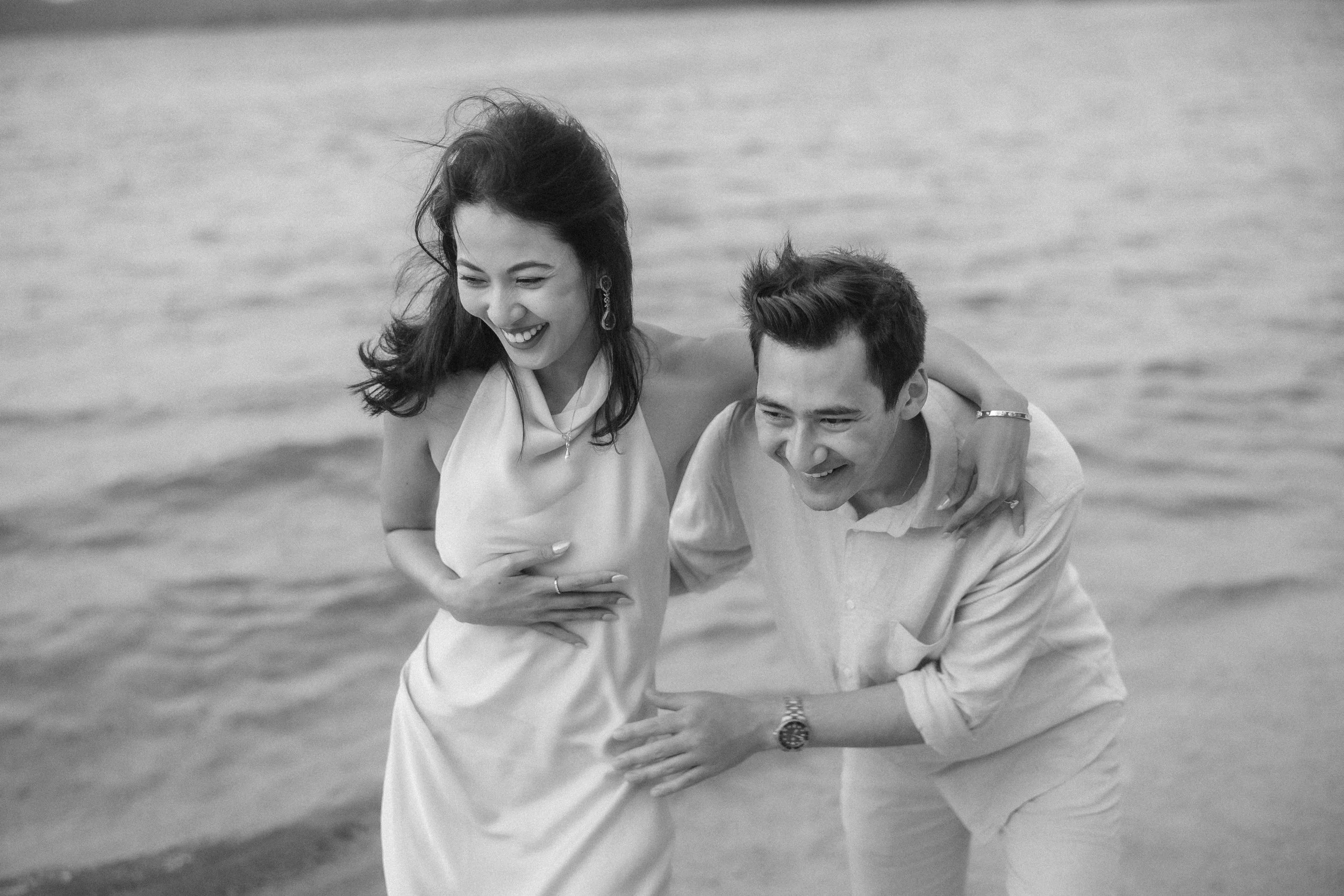 Editorial black and white photograph of Brijend and Sumi laughing together on the beach during their Puerto Rico marriage proposal experience