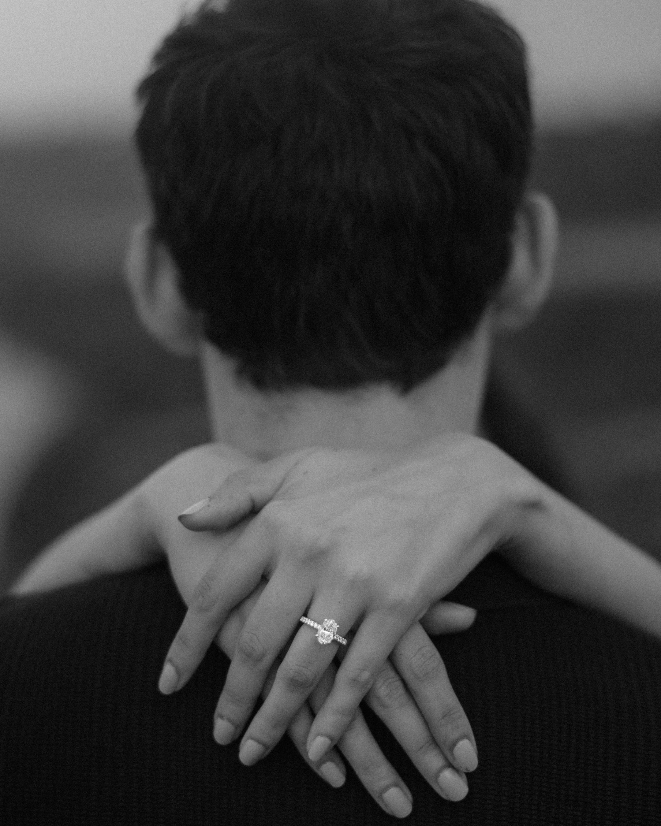 Bride showing her oval diamond engagement ring while embracing her fiancé after a surprise marriage proposal at Royal Isabela in Puerto Rico.