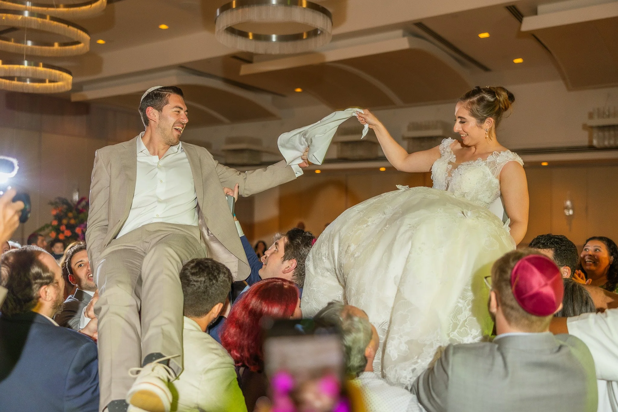 Bride and groom on chairs during the Horah, a Jewish wedding tradition at La Concha Resort shot by a Puerto Rico wedding photographer