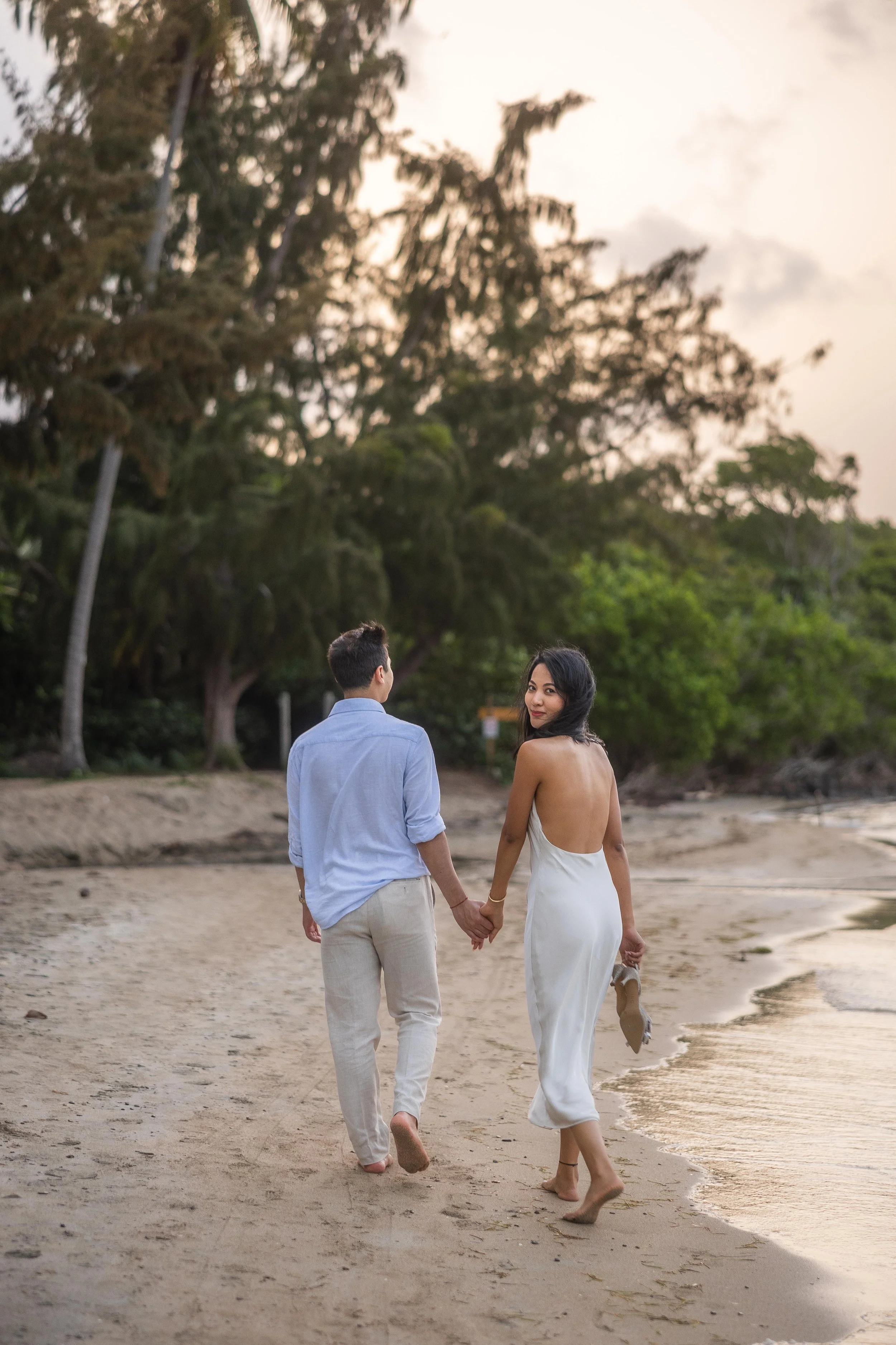 Brijend and Sumi walk barefoot along Seven Seas Beach in Fajardo, Puerto Rico, during their destination engagement photography session.