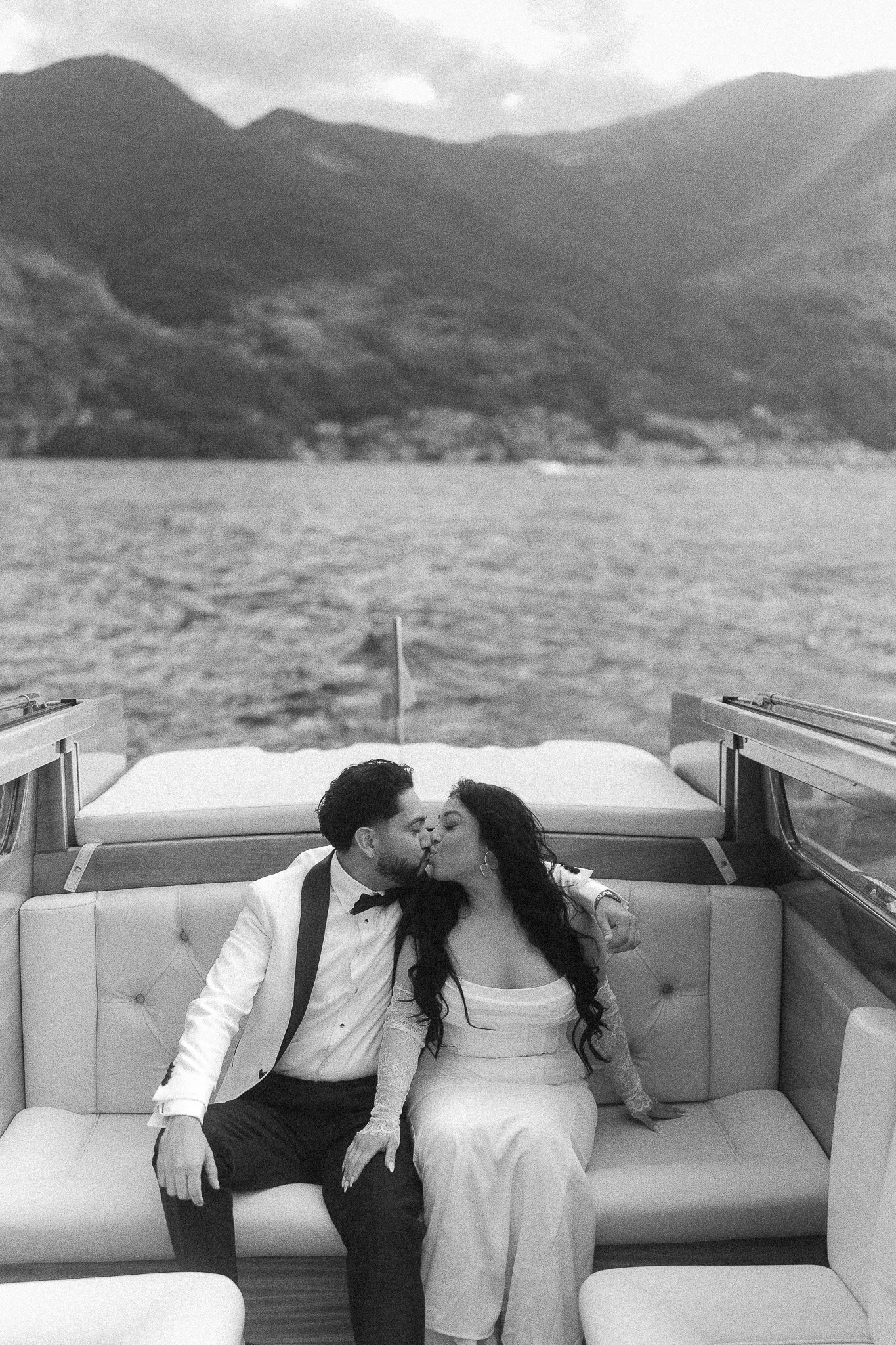 Black and white portrait of a couple kissing on a boat in Lake Como during their luxury elopement at Villa del Balbianello shot by a destination wedding photographer