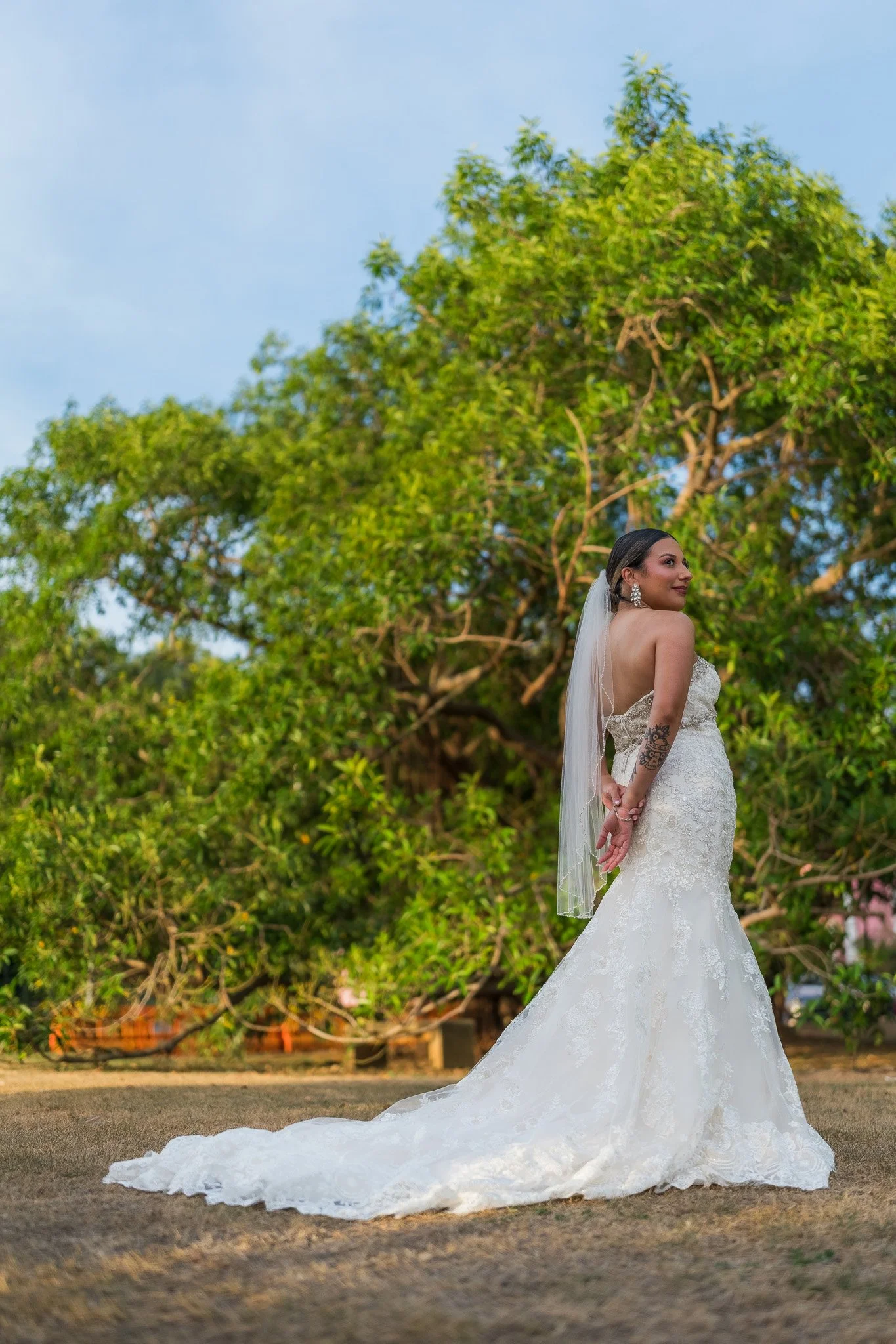Bride posing in her wedding gown beneath towering tropical trees during a luxury destination elopement portrait session in Old San Juan, Puerto Rico.
