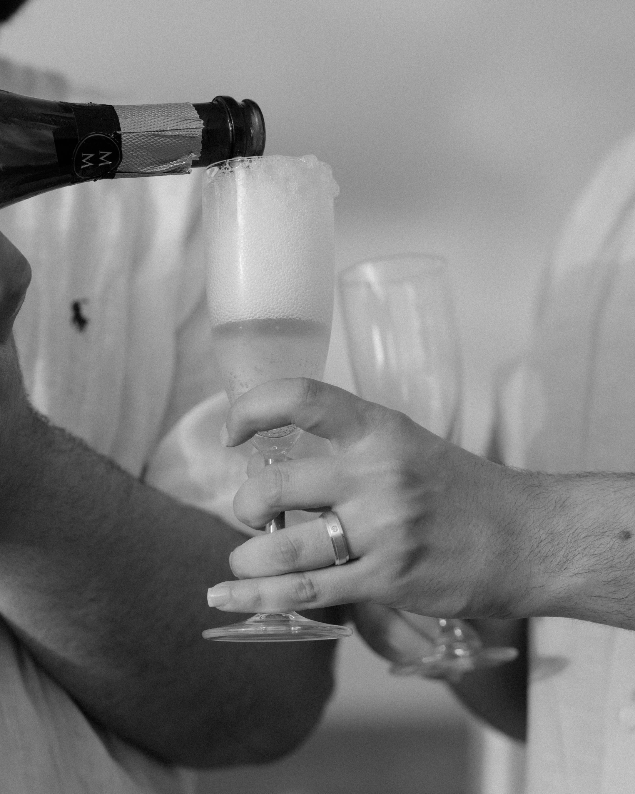 Champagne is poured into flutes as two newly engaged men celebrate their successful LGBT marriage proposal overlooking the Caribbean Sea at Escambrón Beach, Puerto Rico.