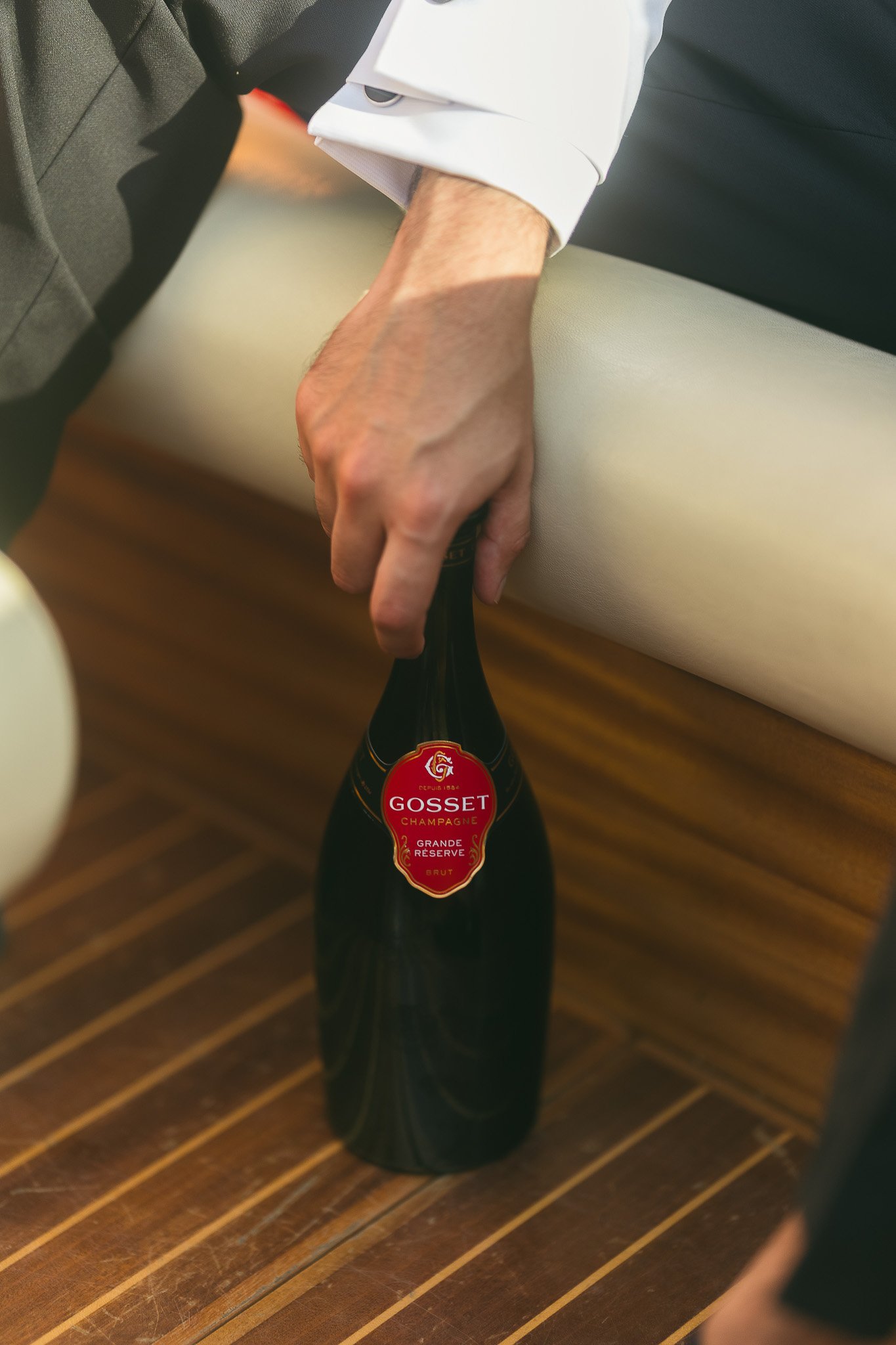 Groom holding onto a champagne bottle on a boat in Lake Como, Italy during his editorial elopement