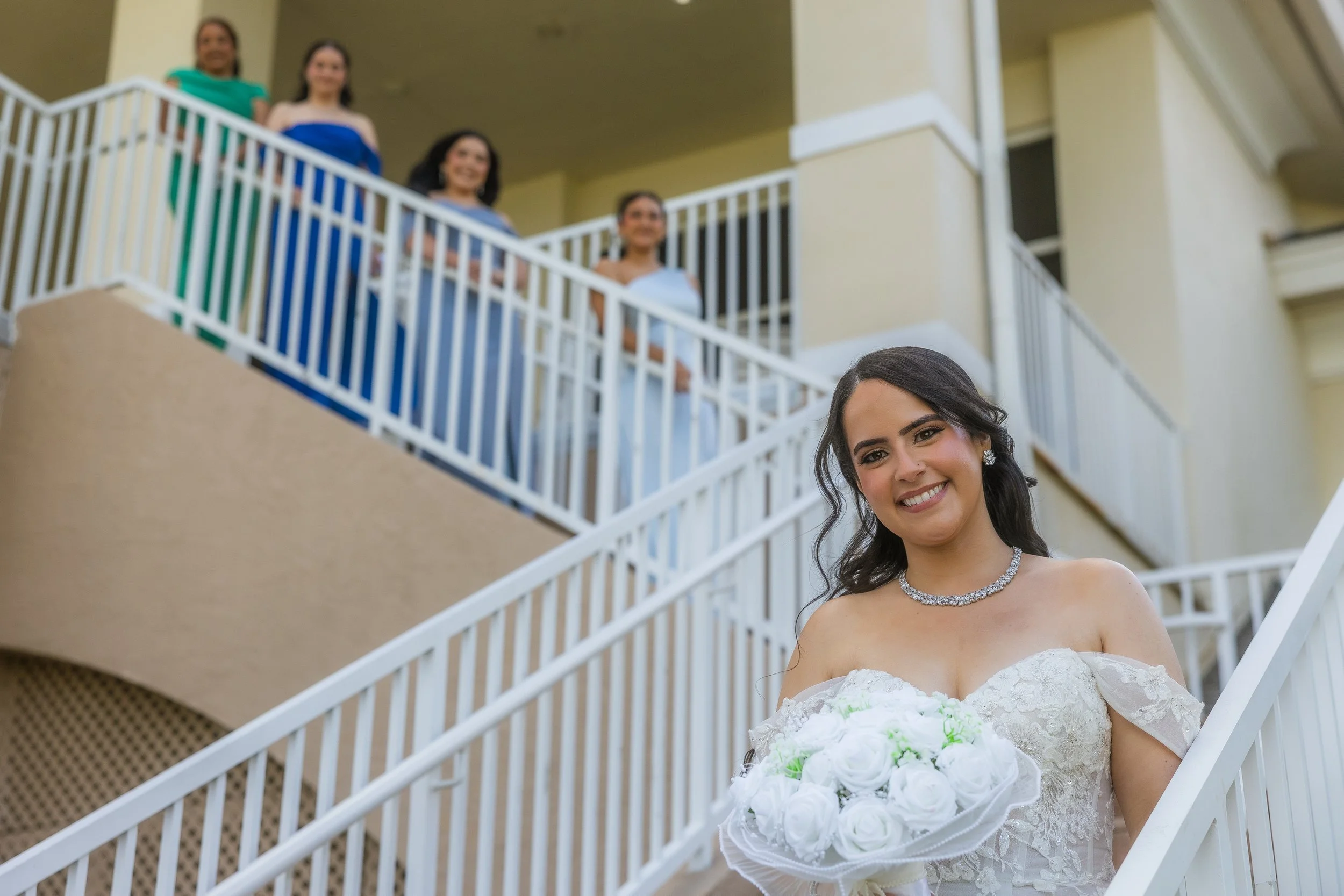 Bride on the stairs of the Indian Spring Country Club posing with her bridesmaids for the camera of a luxury wedding photographer in West Palm Beach.