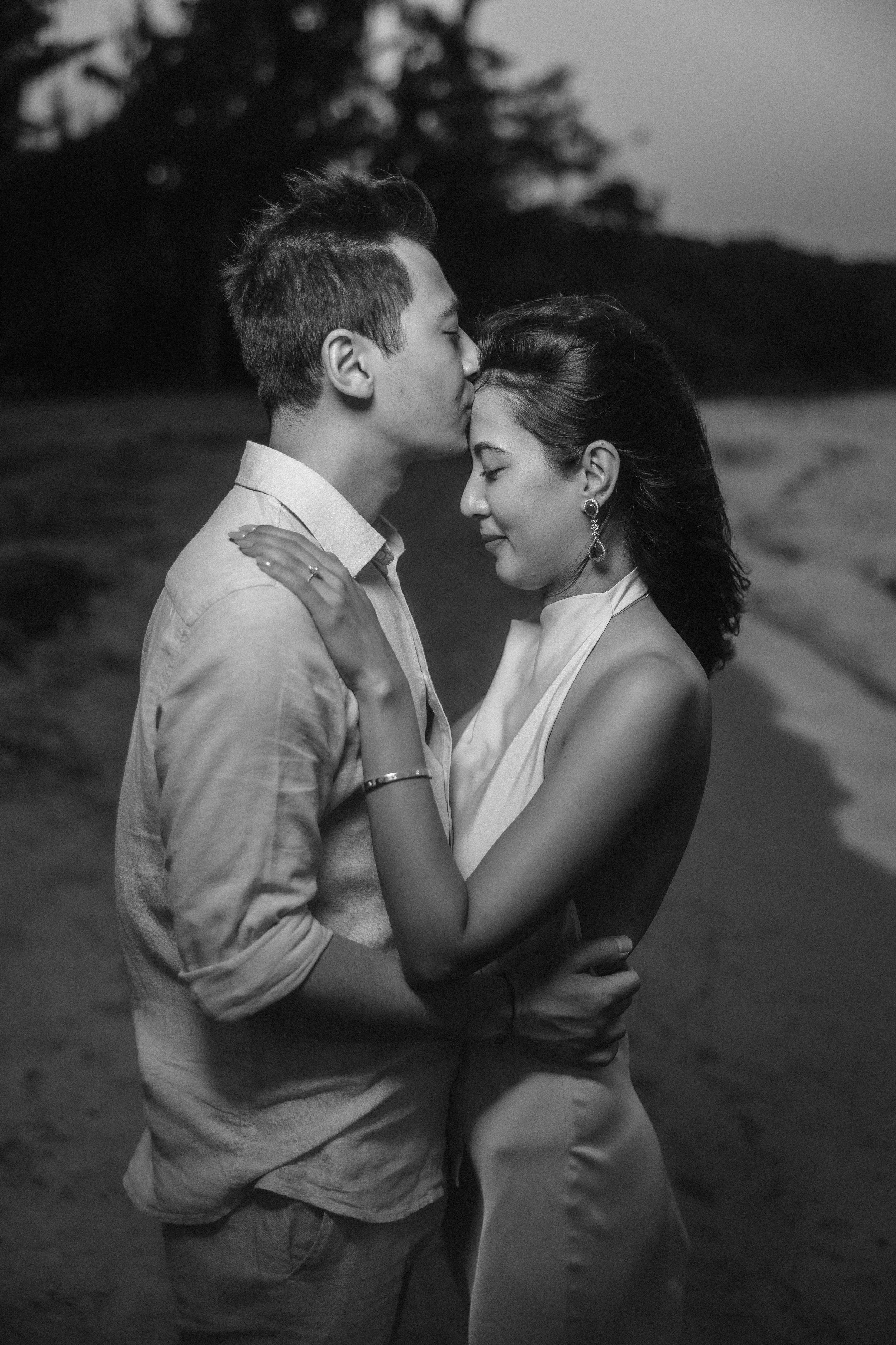 Artistic black and white beach portrait of Brijend and Sumi embracing at dusk during their luxury marriage proposal photography session in Puerto Rico.