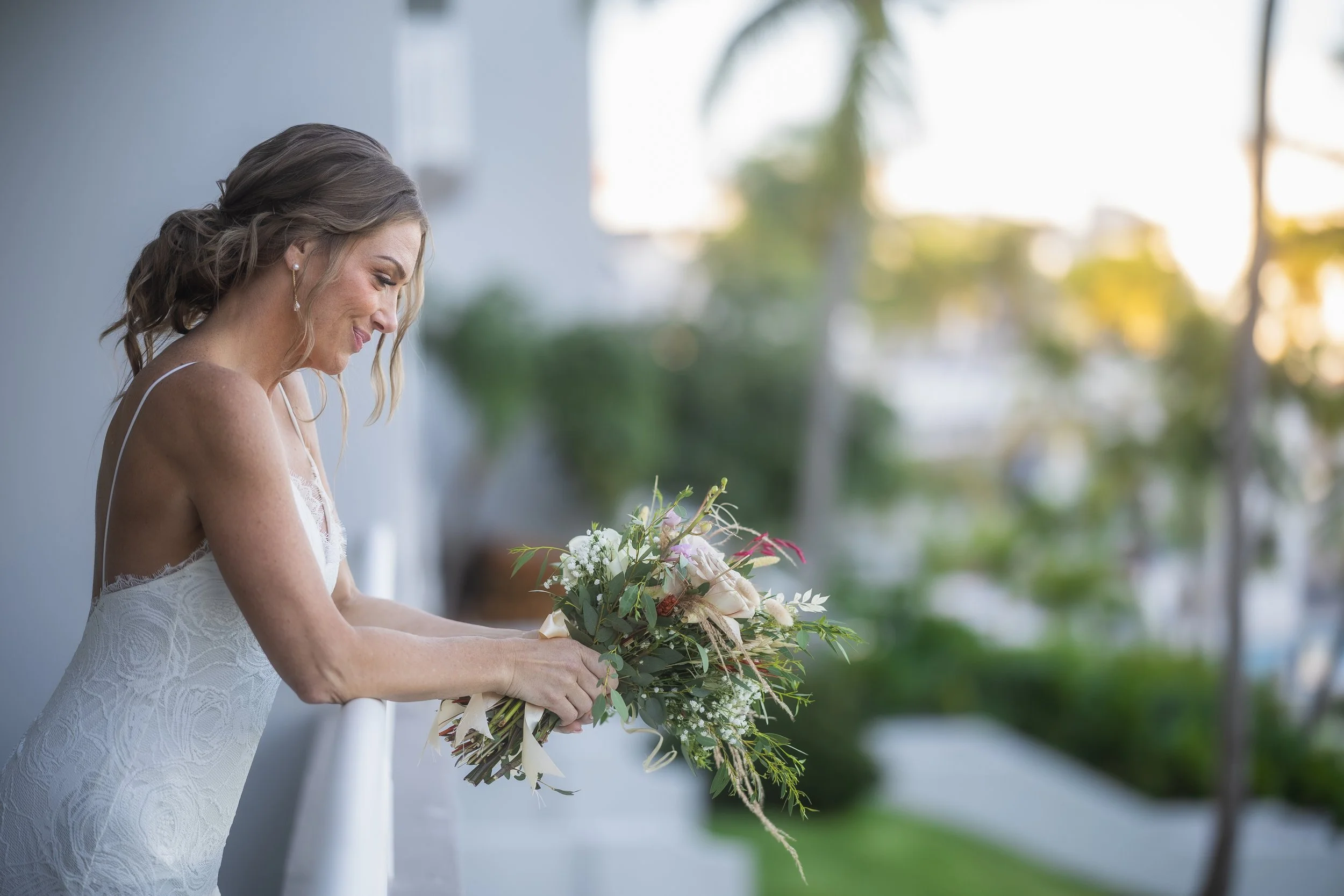 Bride posing on balcony overlooking oceanfront ceremony site at El Conquistador Resort.