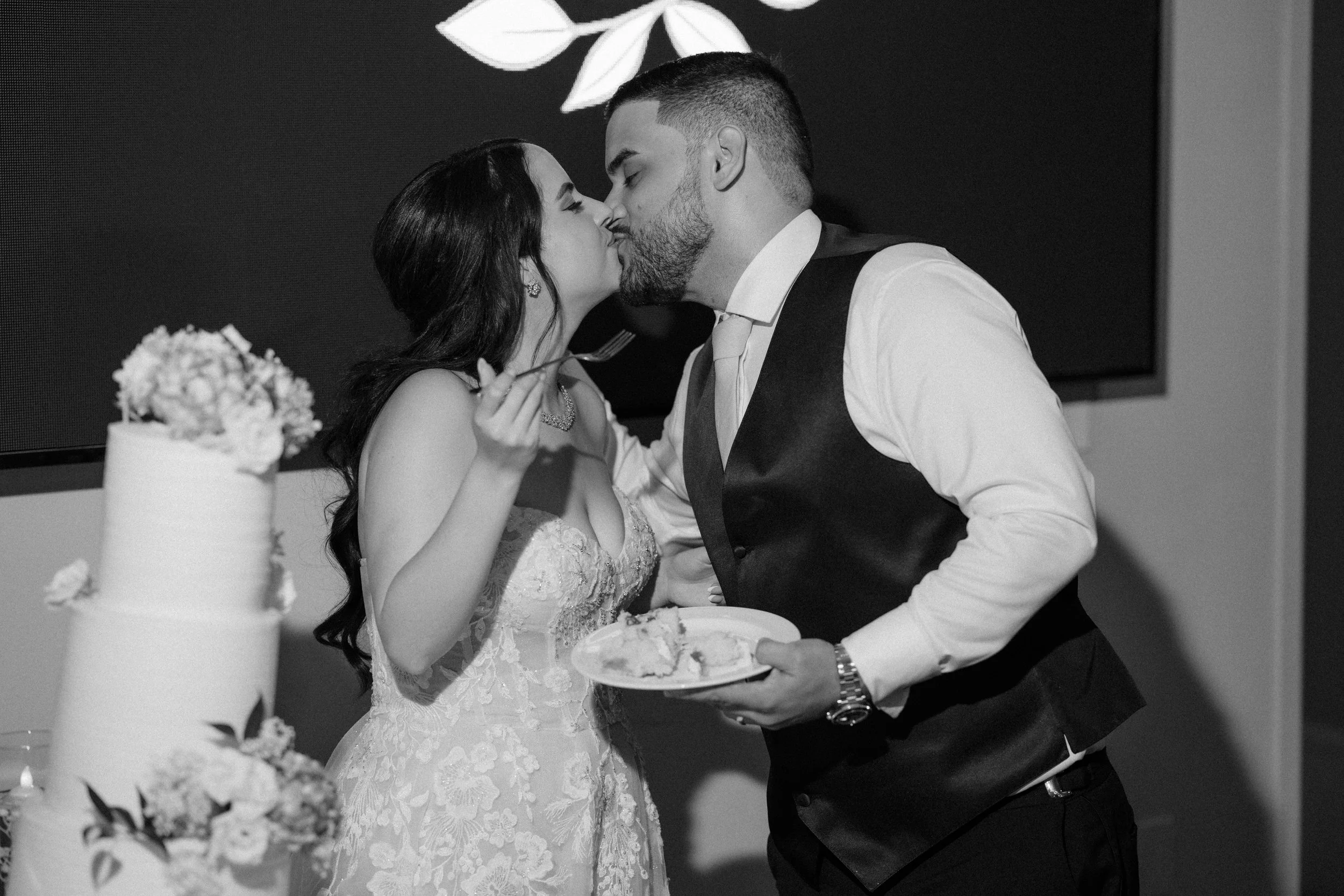 Bride and groom cutting the cake and kissing at Indian Spring Country Club during their luxury wedding in South Florida.
