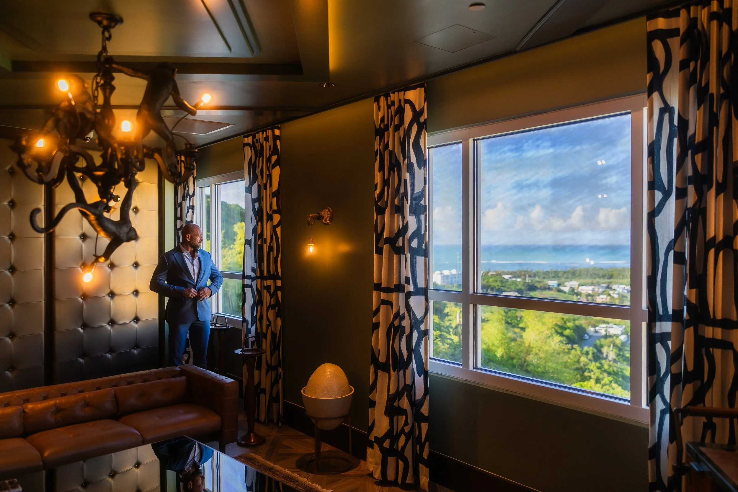 Groom standing by window inside cigar lounge at El Conquistador Resort in Puerto Rico.