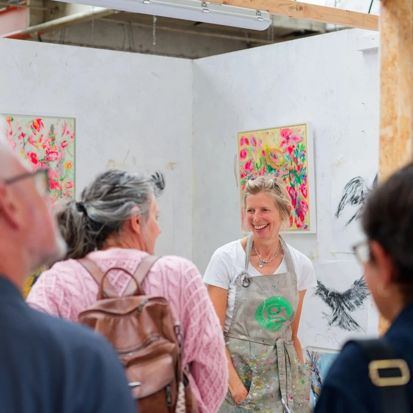 Image of female artist in her studio chatting with exhibition visitors