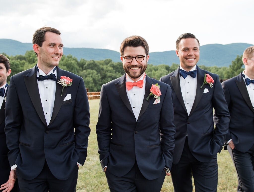 groom and groomsmen in dark suits with coral boutonnieres