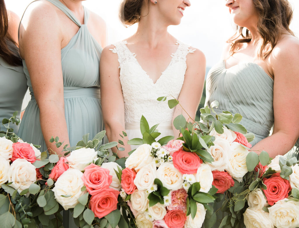 wedding bouquets of coral and white held by bride and bridesmaids