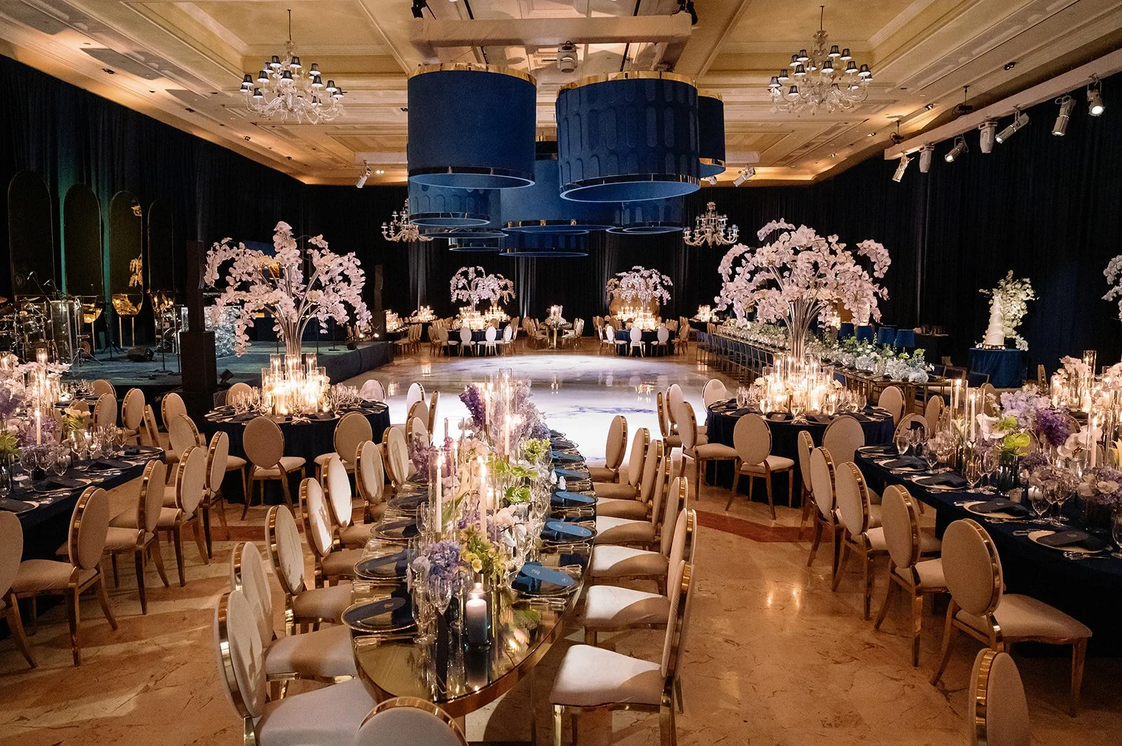 Luxury wedding reception at The Breakers Palm Beach with navy overhead installations, candlelit tables, white orchid florals, and a custom bars and dance floor designed and planned by Roxanne Bellamy & Co.