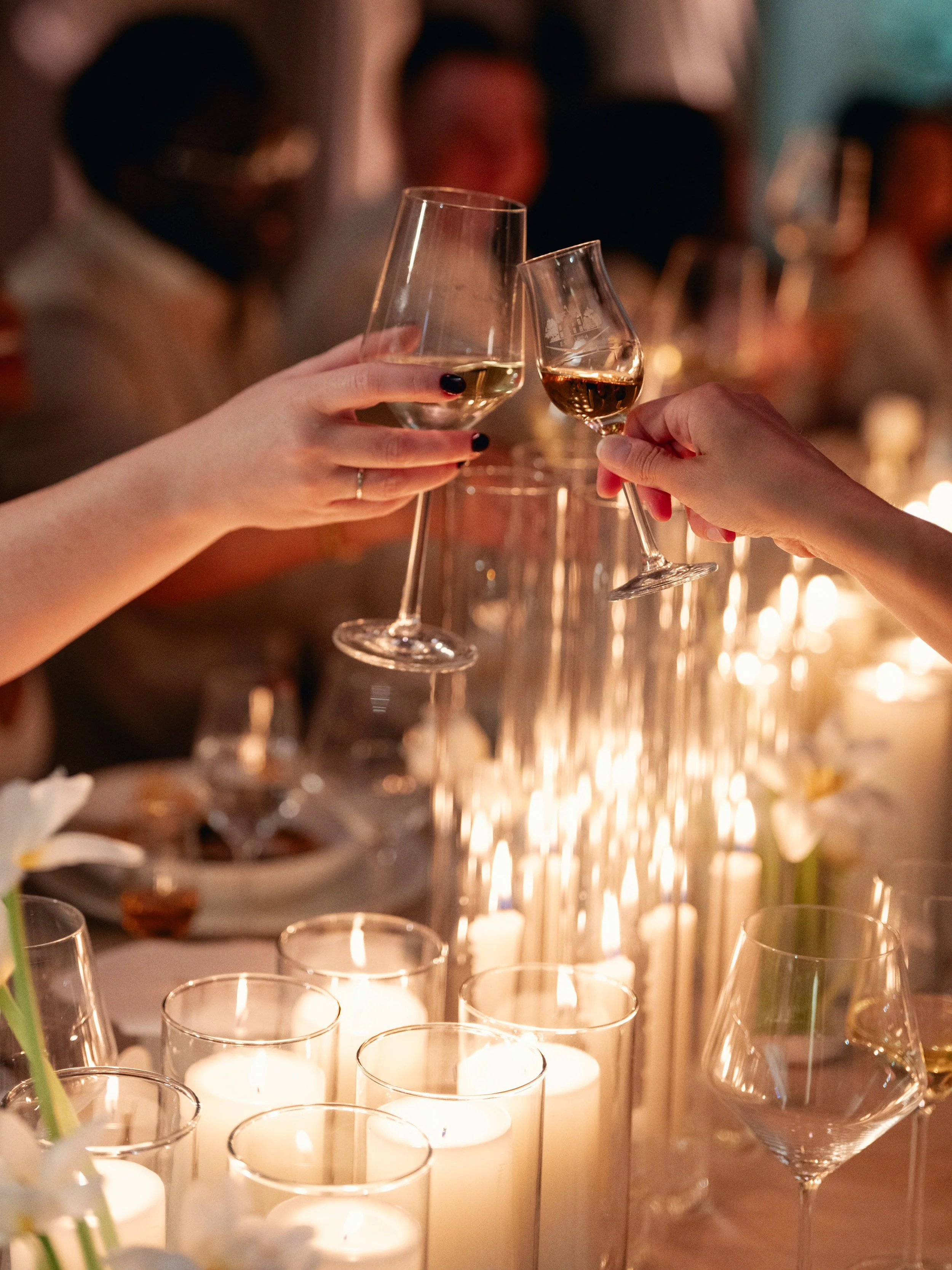 Guests toast over a candlelit dinner table during a luxury event experience designed and planned by Roxanne Bellamy & Co.