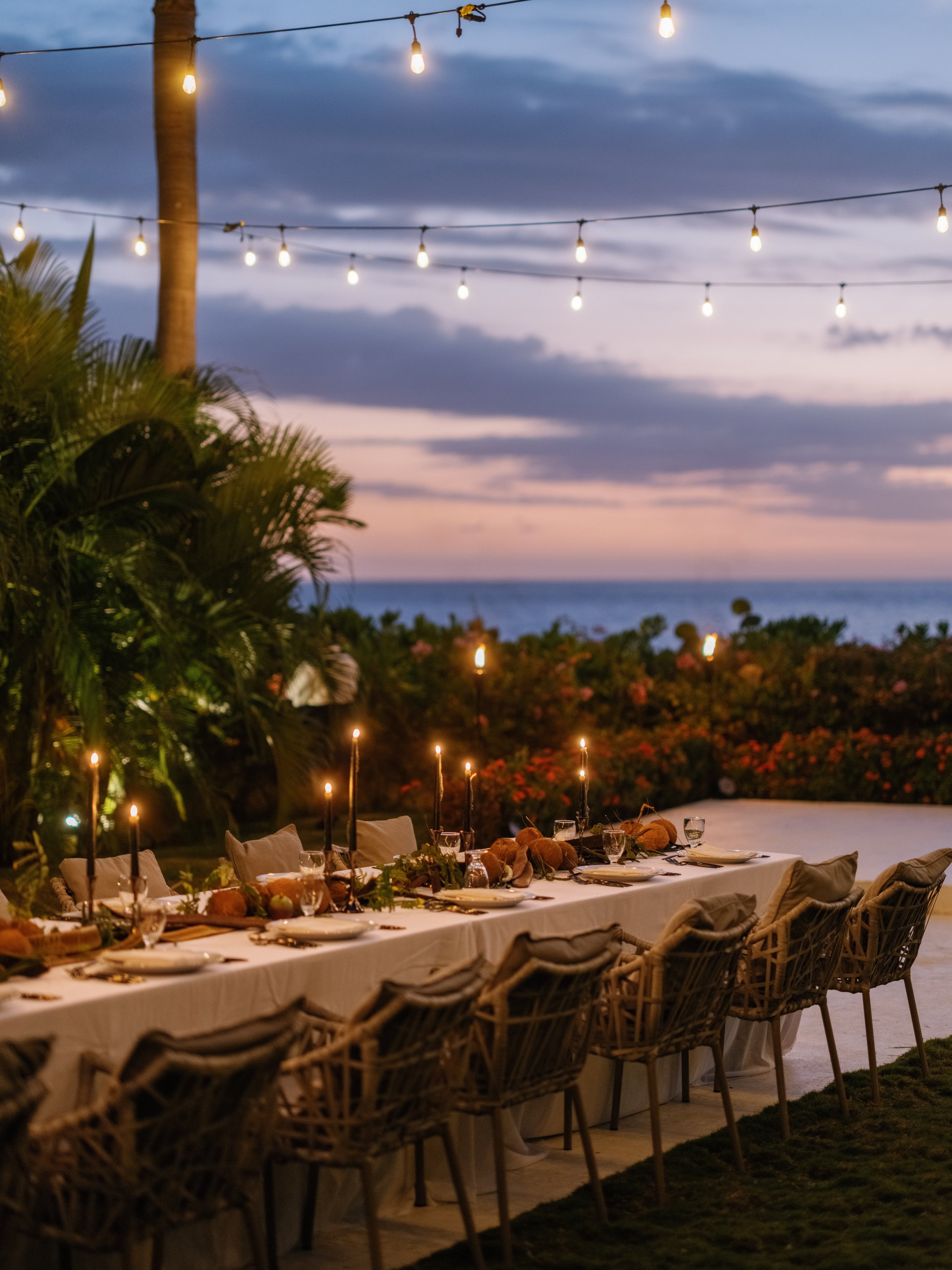 Candlelit outdoor dinner table at sunset overlooking the Caribbean Sea in Negril, Jamaica.