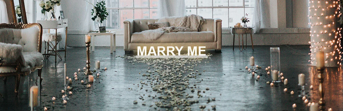 A beautiful proposal scene, with Marry Me LED Letter Light sign, candles and petals.