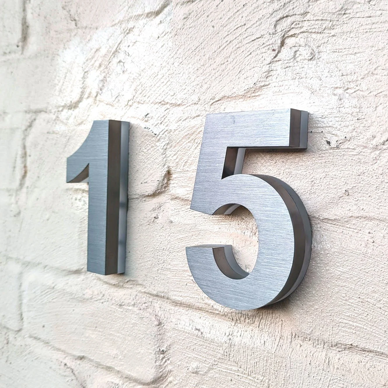 Brushed silver metal backlit led house number on brick wall